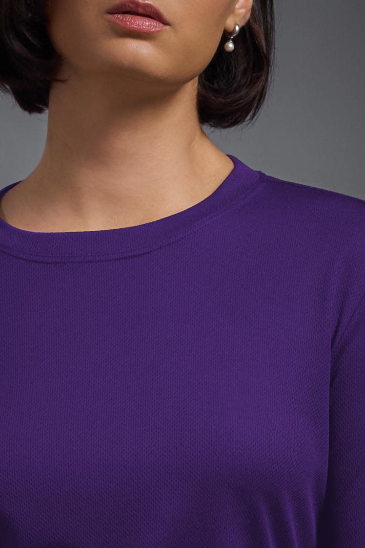 A female model wearing the women's Oxymesh Long Sleeve Tech Tee in the color dark purple, made out of 100% polyester, showing the relaxed fit from a collar close-up view. This shirt is breathable, quick-drying, moisture-wicking, and made in the USA. #dark-purple