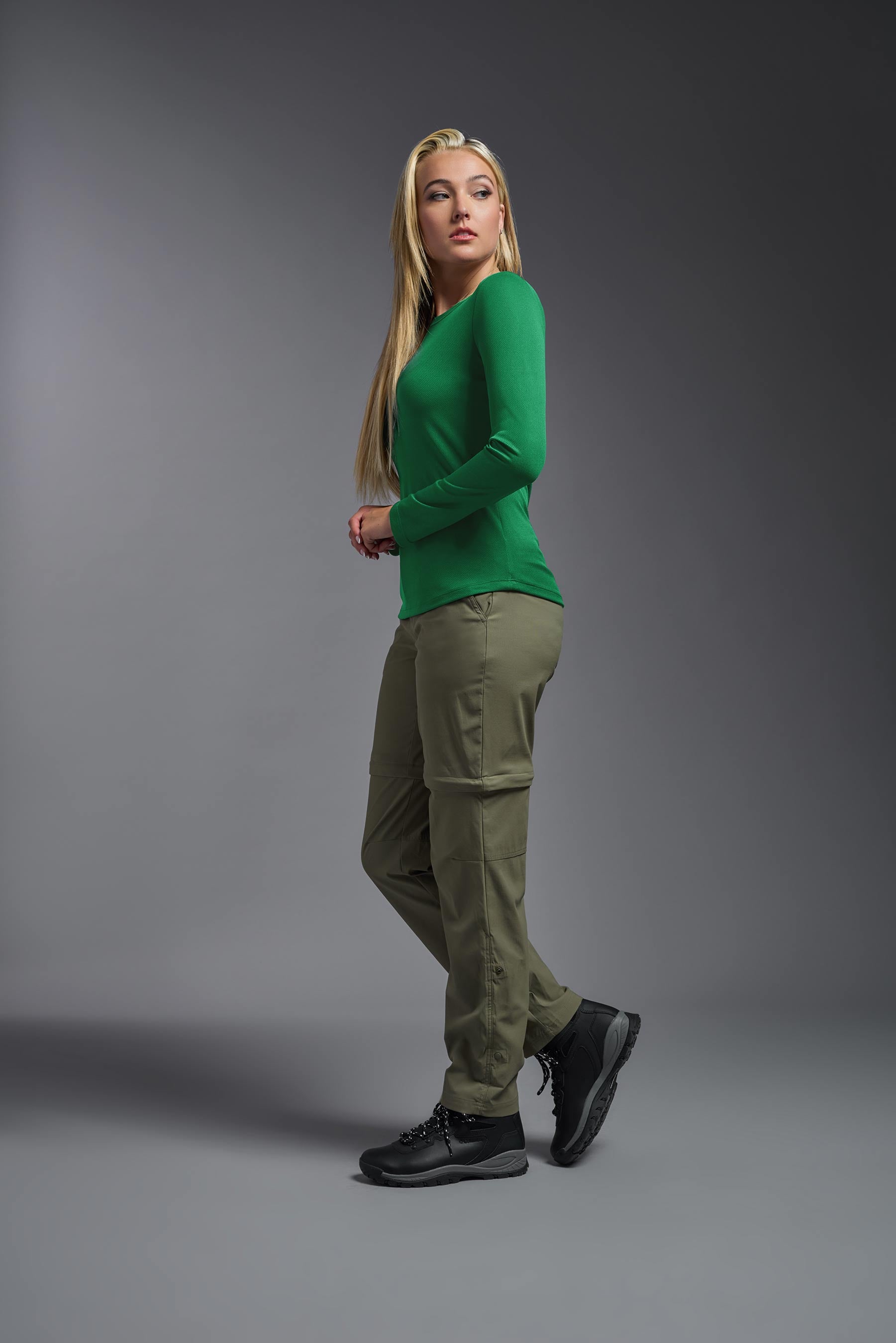 A female model wearing the women's Oxymesh Long Sleeve Tech Tee in the color kelly green, made out of 100% polyester, showing the relaxed fit from a side view. This shirt is breathable, quick-drying, moisture-wicking, and made in the USA. #kelly-green