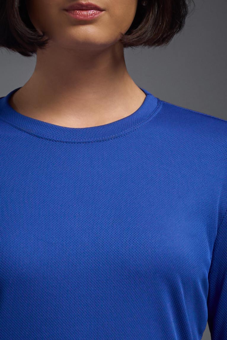 A female model wearing the women's Oxymesh Long Sleeve Tech Tee in the color royal blue, made out of 100% polyester, showing the relaxed fit from a front collar close-up view. This shirt is breathable, quick-drying, moisture-wicking, and made in the USA. #royal-blue