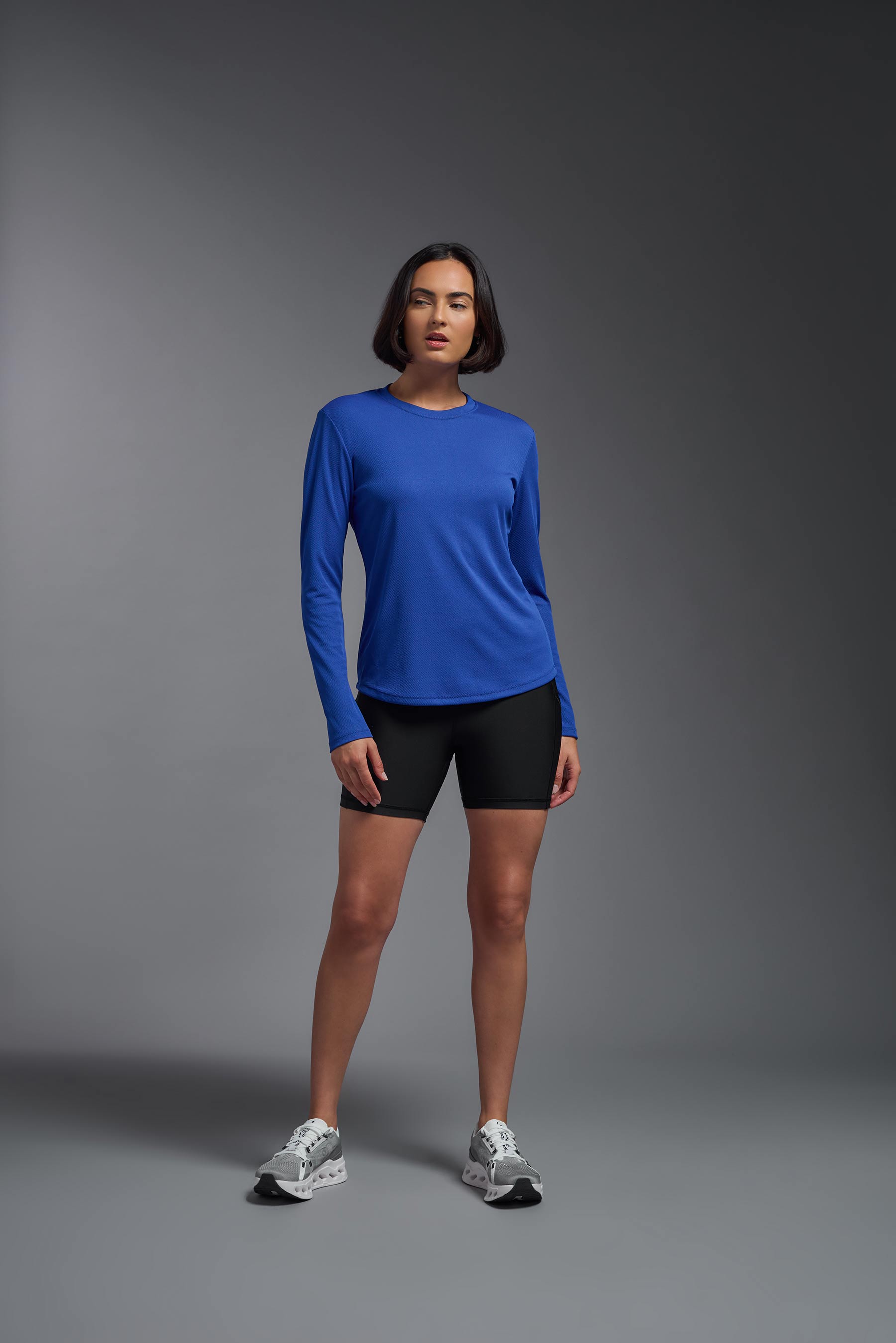 A female model wearing the women's Oxymesh Long Sleeve Tech Tee in the color royal blue, made out of 100% polyester, showing the relaxed fit from a front view. This shirt is breathable, quick-drying, moisture-wicking, and made in the USA. #royal-blue
