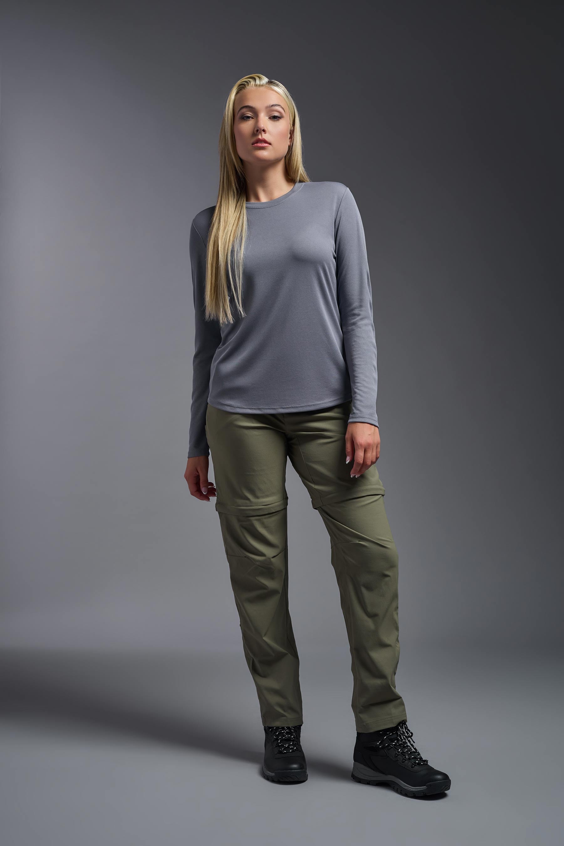 A female model wearing the women's Oxymesh Long Sleeve Tech Tee in the color steel, made out of 100% polyester, showing the relaxed fit from a front view. This shirt is breathable, quick-drying, moisture-wicking, and made in the USA. #steel-gray