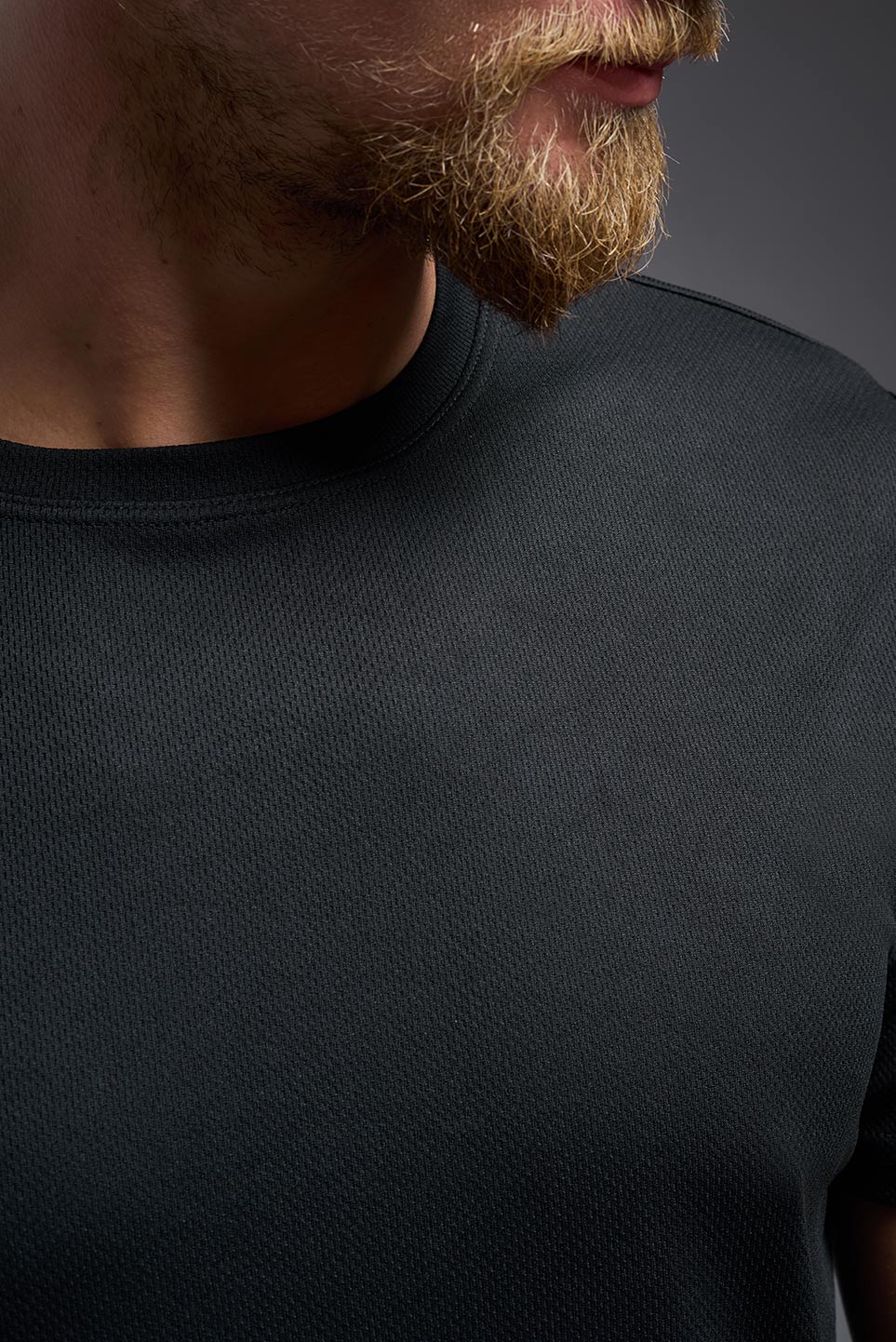A male model wearing the men's Oxymesh Long Sleeve Tech Tee Imported Version in the color black, made out of 100% polyester, showing the relaxed fit from a close-up collar front view. This shirt is breathable, quick-drying, moisture-wicking, and Imported for a better price on bulk apparel. #black