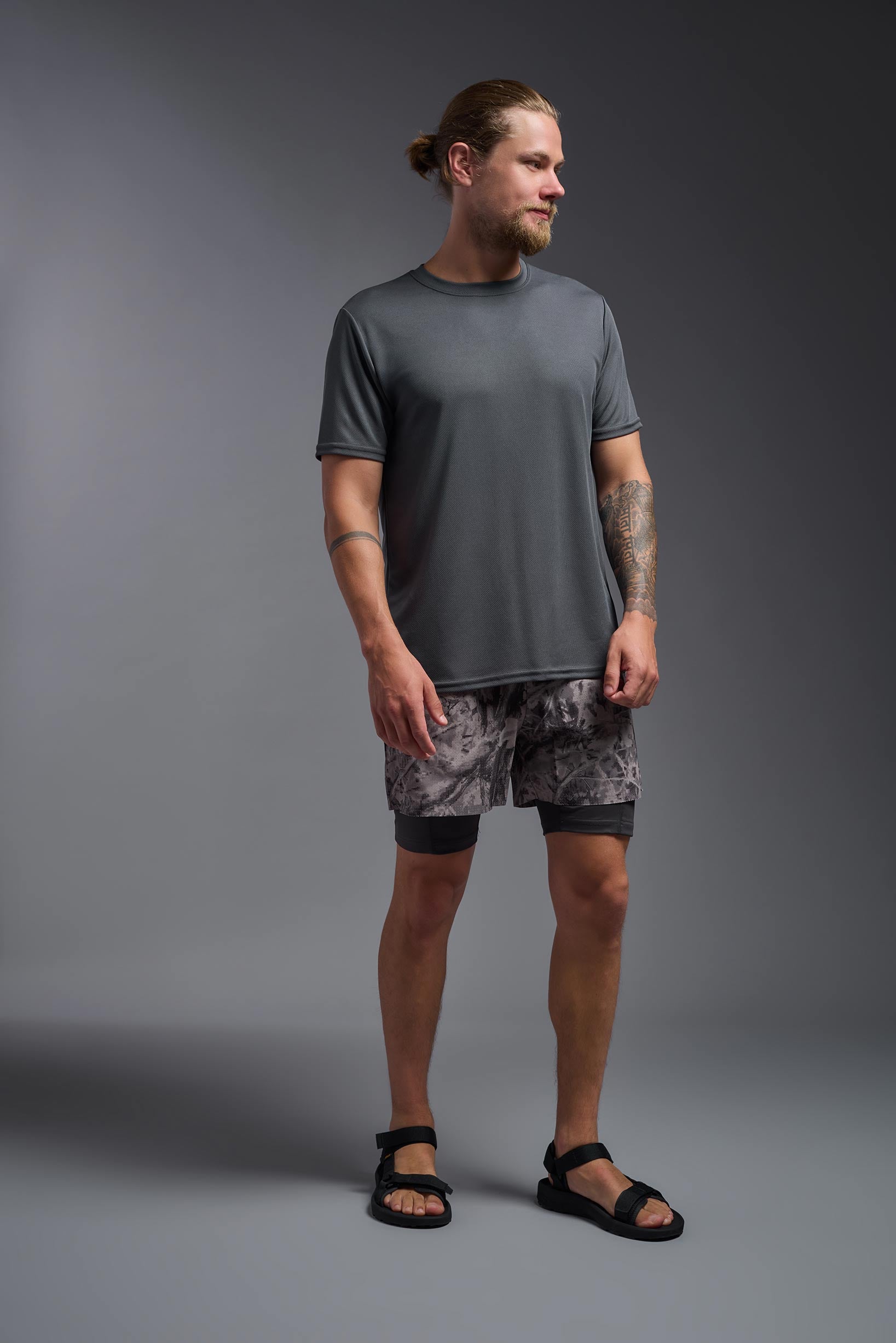 A male model wearing the men's Oxymesh Long Sleeve Tech Tee Imported Version in the color graphite gray, made out of 100% polyester, showing the relaxed fit from a front view. This shirt is breathable, quick-drying, moisture-wicking, and Imported for a better price on bulk apparel. #graphite-gray
