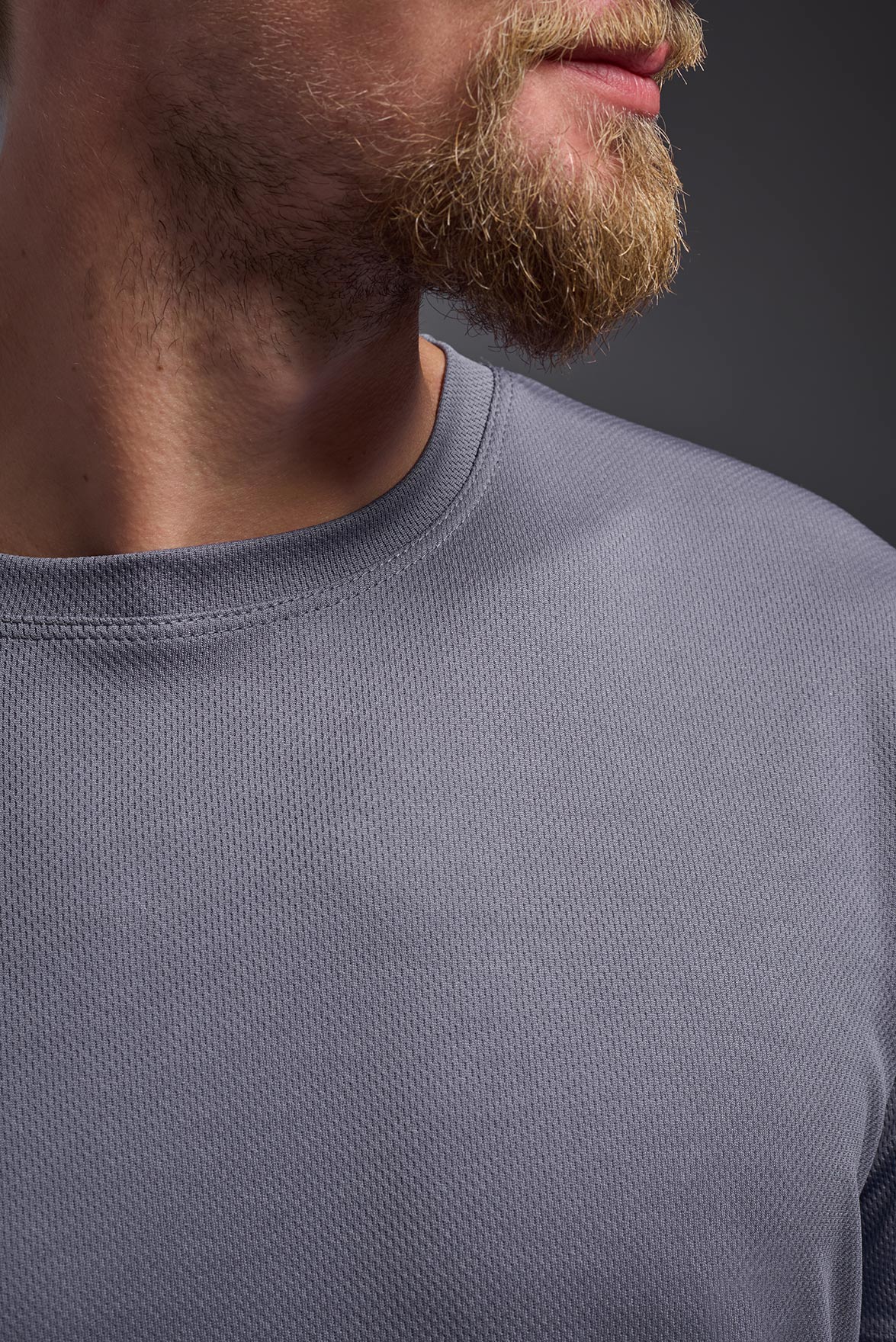 A male model wearing the men's Oxymesh Long Sleeve Tech Tee Imported Version in the color steel gray, made out of 100% polyester, showing the relaxed fit from a close-up collar front view. This shirt is breathable, quick-drying, moisture-wicking, and Imported for a better price on bulk apparel. #steel-gray