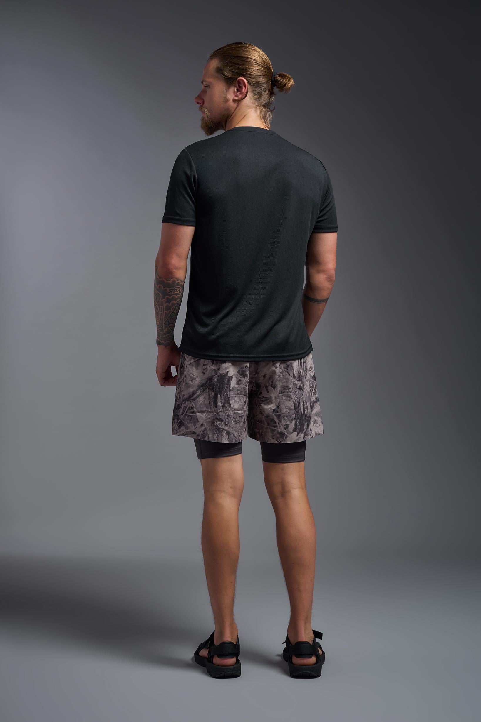 A male model wearing the men's Oxymesh Crewneck Tech Tee in the color black, made out of 100% polyester, showing the relaxed fit from a back view. This shirt is breathable, wicks away moisture, quick-dries, and is made in the USA. #black