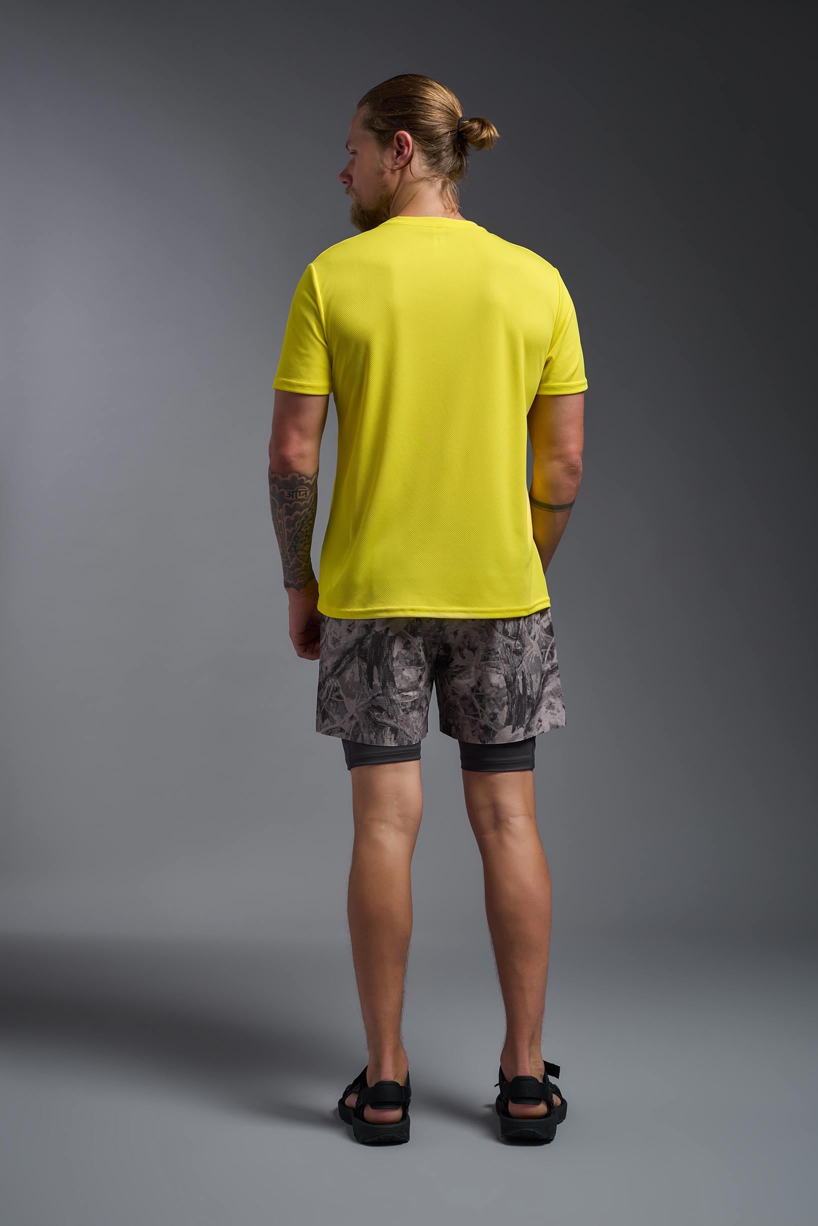 A male model wearing the men's Oxymesh Crewneck Tech Tee in the color bright yellow, made out of 100% polyester, showing the relaxed fit from a back view. This shirt is breathable, wicks away moisture, quick-dries, and is made in the USA. #bright-yellow