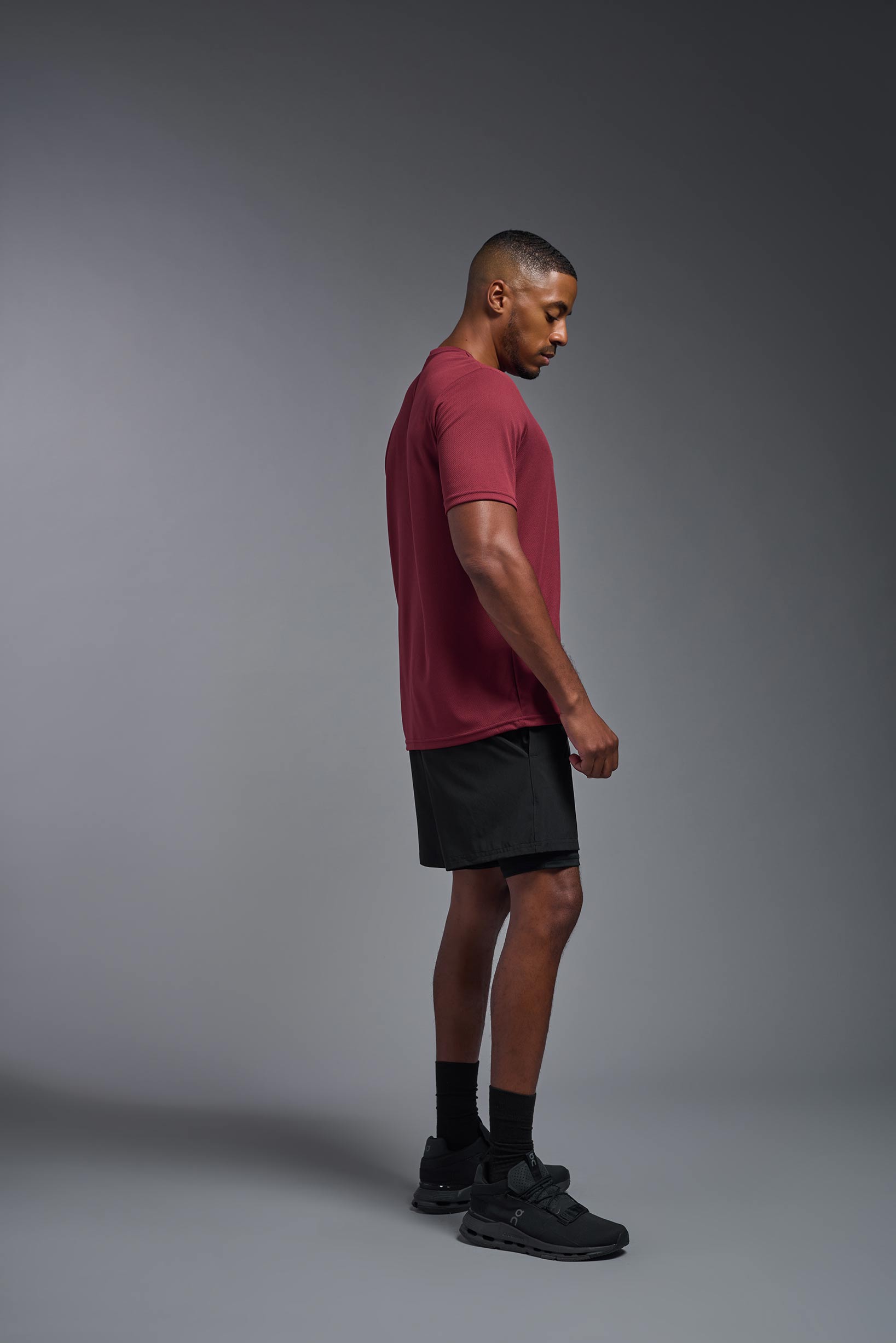 A male model wearing the men's Oxymesh Crewneck Tech Tee in the color cardinal made out of 100% polyester, showing the relaxed fit from a side view. This shirt is breathable, wicks away moisture, quick-dries, and is made in the USA. #cardinal