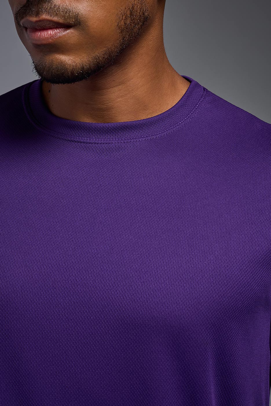 A male model wearing the men's Oxymesh Crewneck Tech Tee in the color dark purple made out of 100% polyester, showing the relaxed fit from a close-up collar view. This shirt is breathable, wicks away moisture, quick-dries, and is made in the USA. #dark-purple
