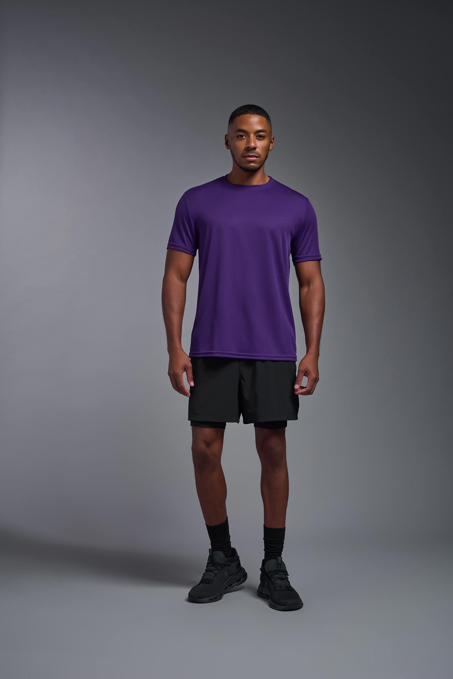 A male model wearing the men's Oxymesh Crewneck Tech Tee in the color dark purple made out of 100% polyester, showing the relaxed fit from a front view. This shirt is breathable, wicks away moisture, quick-dries, and is made in the USA. #dark-purple
