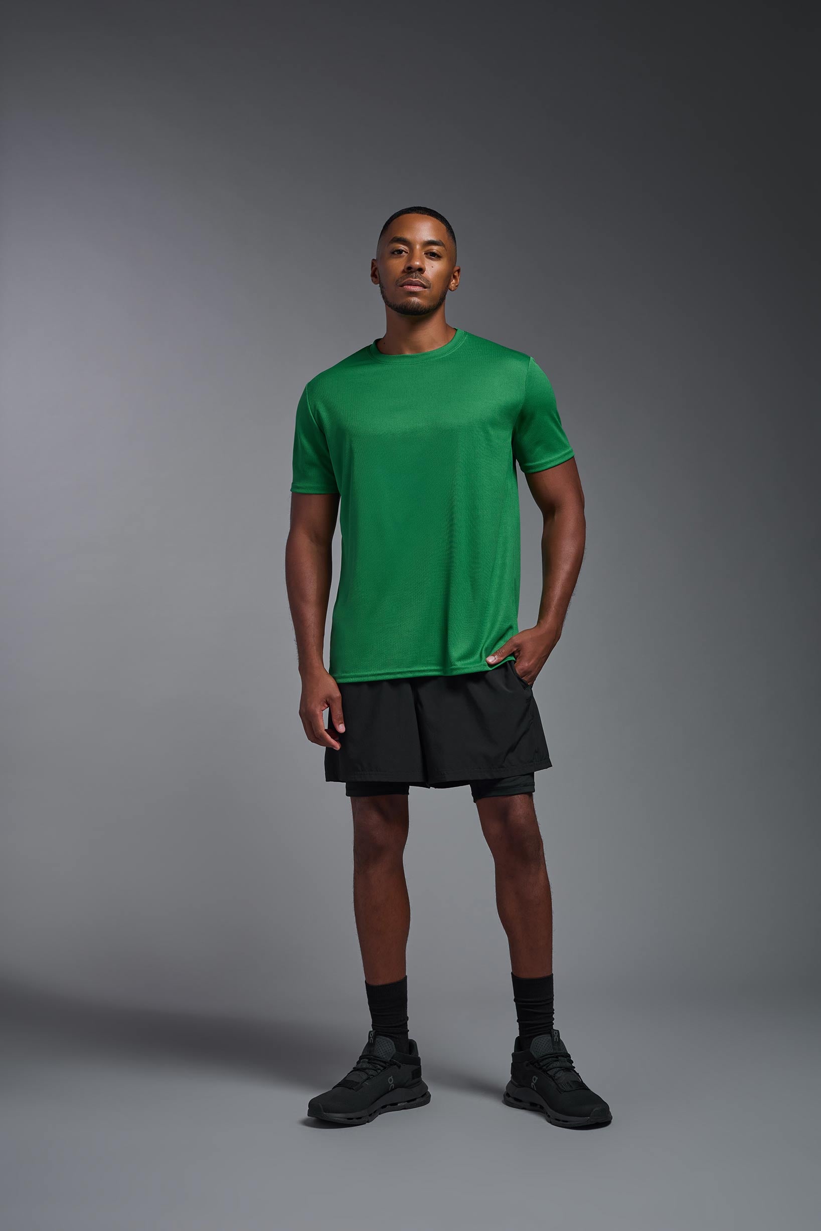 A male model wearing the men's Oxymesh Crewneck Tech Tee in the color kelly green made out of 100% polyester, showing the relaxed fit from a front view. This shirt is breathable, wicks away moisture, quick-dries, and is made in the USA. #kelly-green