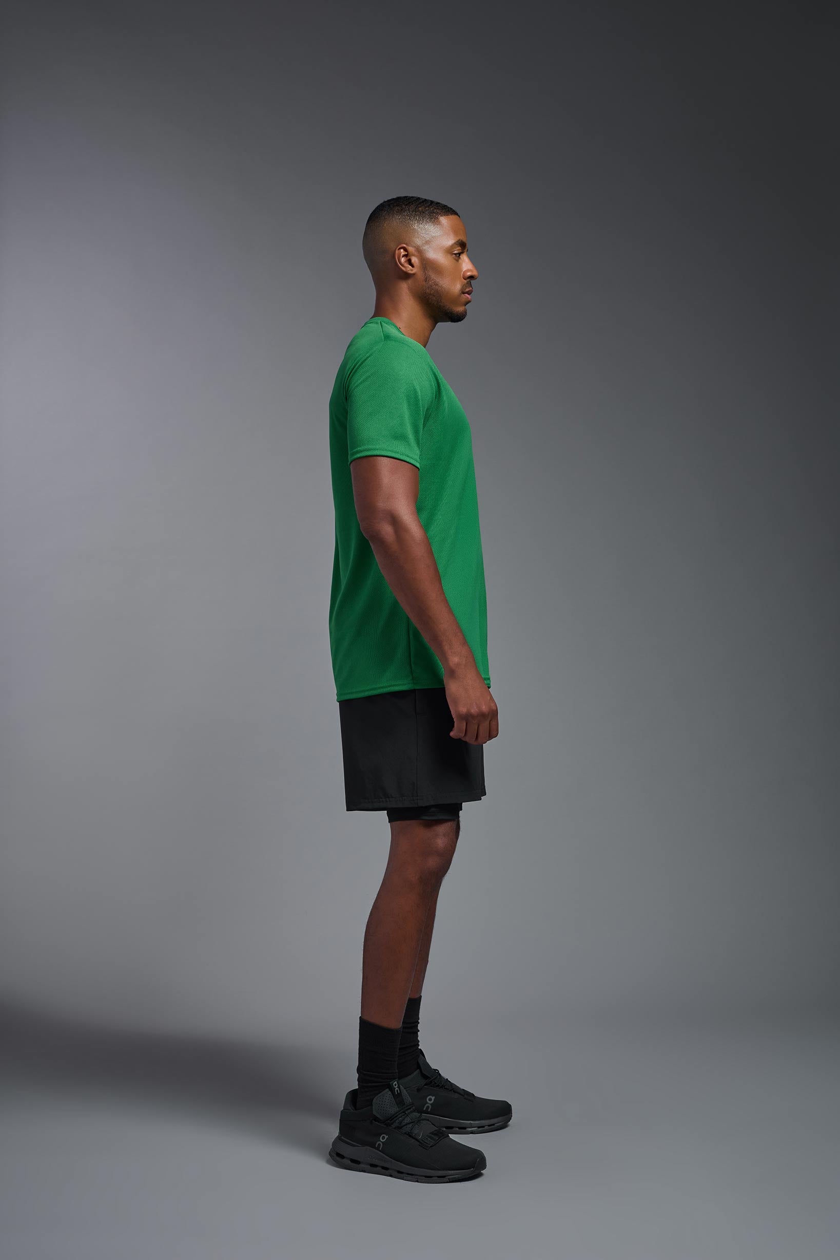 A male model wearing the men's Oxymesh Crewneck Tech Tee in the color kelly green made out of 100% polyester, showing the relaxed fit from a side view. This shirt is breathable, wicks away moisture, quick-dries, and is made in the USA. #kelly-green