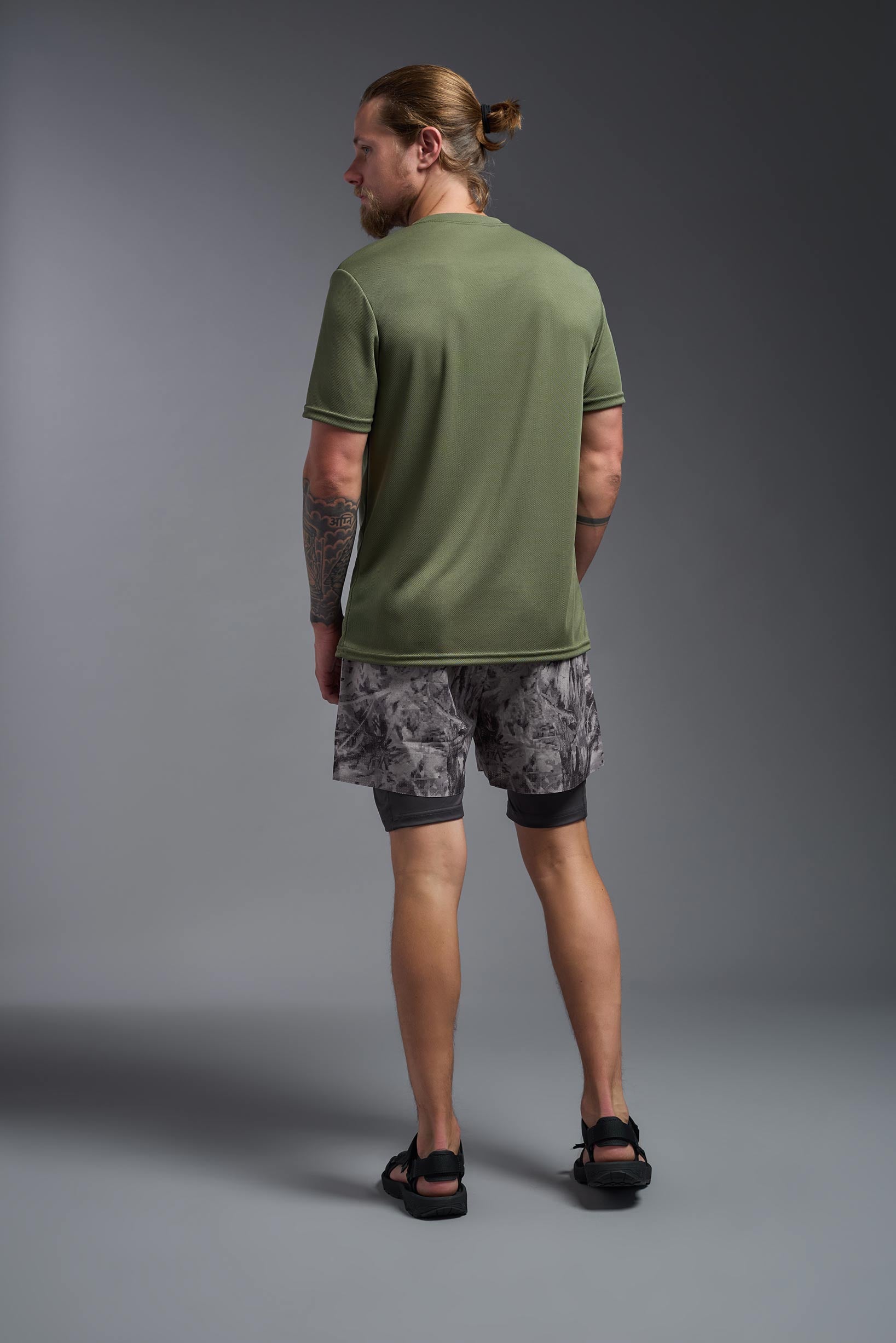 A male model wearing the men's Oxymesh Crewneck Tech Tee in the color military green made out of 100% polyester, showing the relaxed fit from a back view. This shirt is breathable, wicks away moisture, quick-dries, and is made in the USA. #military-green