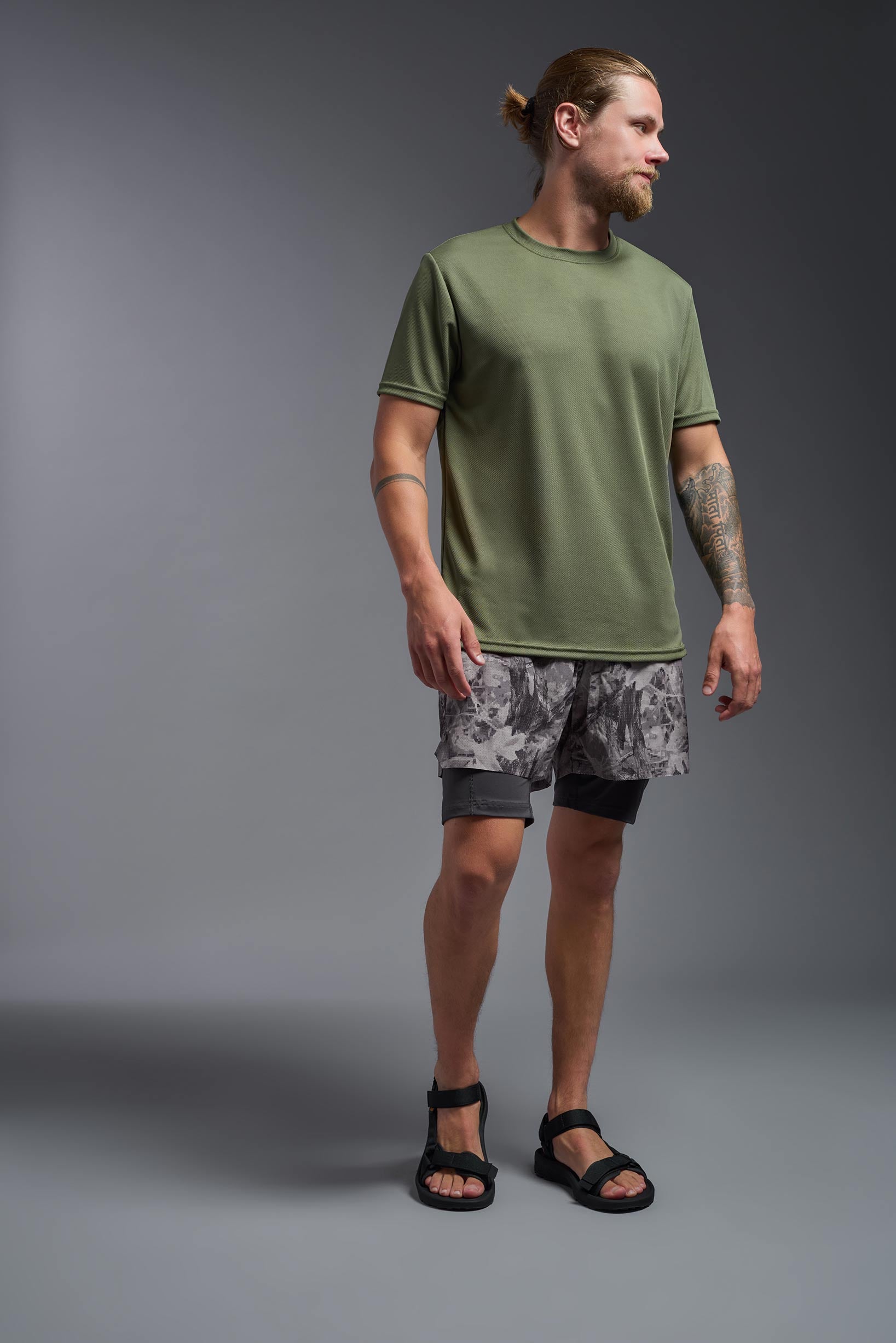 A male model wearing the men's Oxymesh Crewneck Tech Tee in the color military green made out of 100% polyester, showing the relaxed fit from a back view. This shirt is breathable, wicks away moisture, quick-dries, and is made in the USA. #military-green