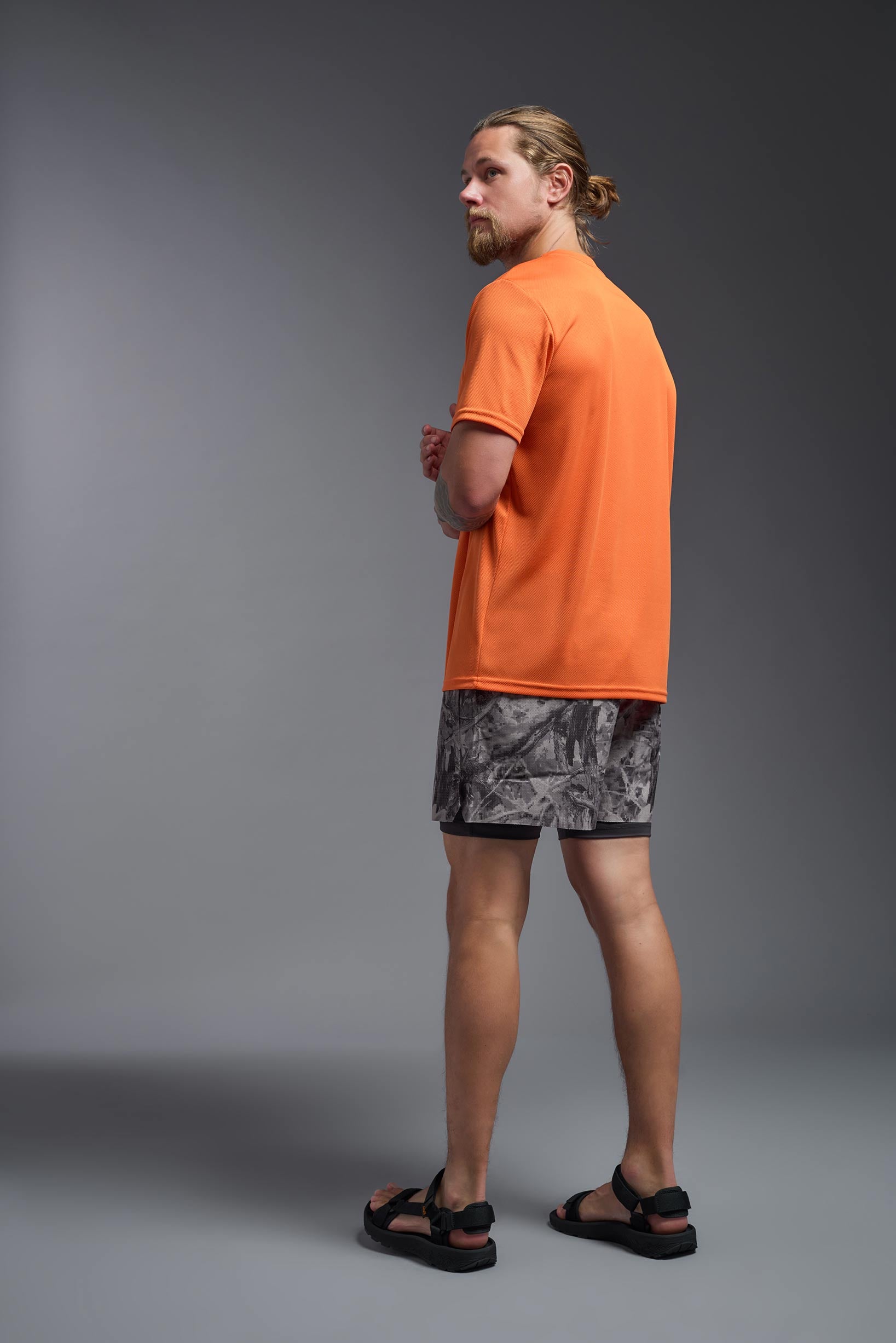 A male model wearing the men's Oxymesh Crewneck Tech Tee in the color orange made out of 100% polyester, showing the relaxed fit from a back view. This shirt is breathable, wicks away moisture, quick-dries, and is made in the USA. #orange