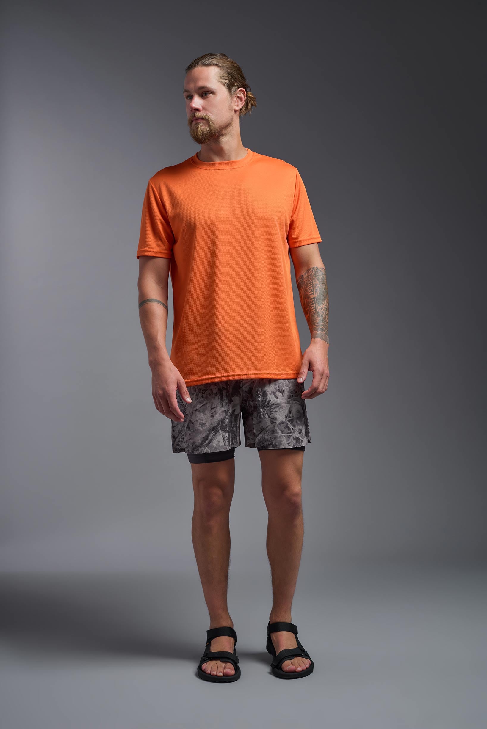 A male model wearing the men's Oxymesh Crewneck Tech Tee in the color orange made out of 100% polyester, showing the relaxed fit from a front view. This shirt is breathable, wicks away moisture, quick-dries, and is made in the USA. #orange