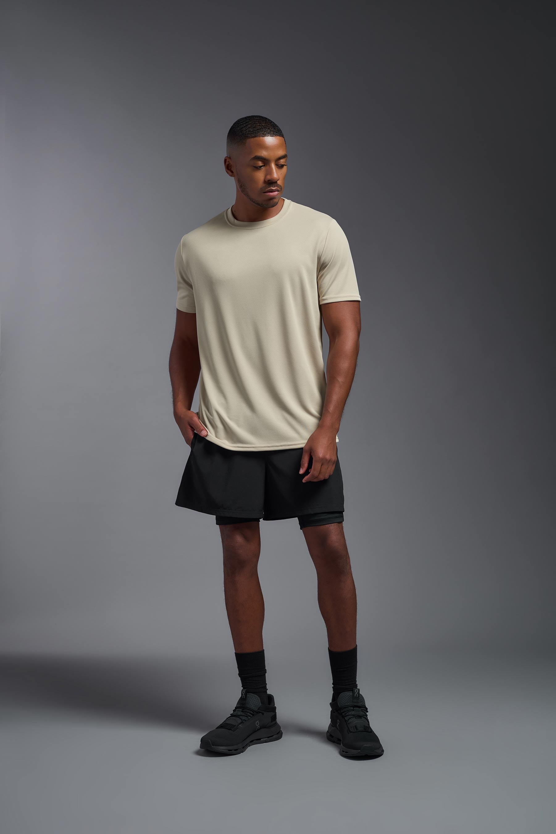 A male model wearing the men's Oxymesh Crewneck Tech Tee in the color sand made out of 100% polyester, showing the relaxed fit from a front view. This shirt is breathable, wicks away moisture, quick-dries, and is made in the USA. #sand