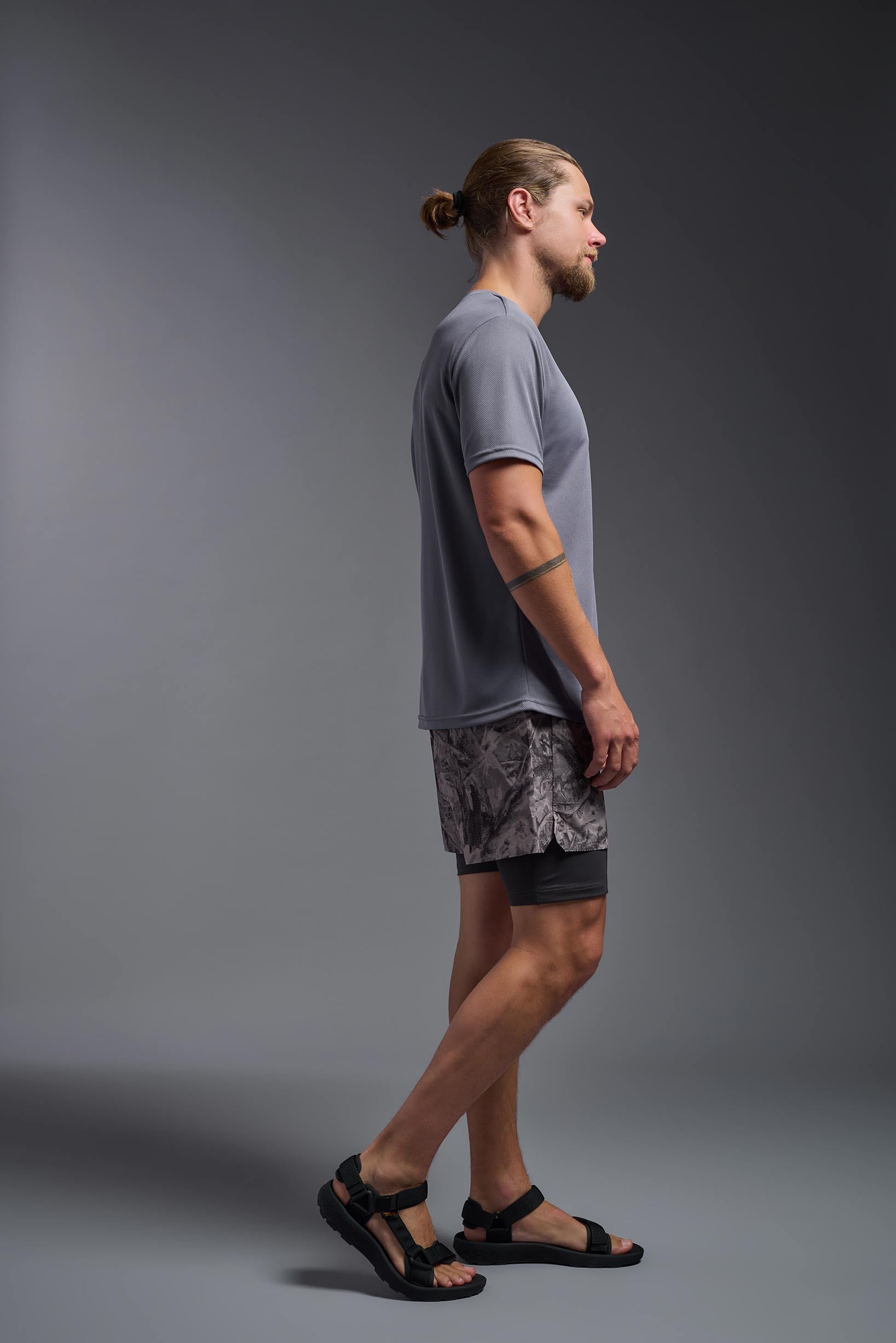 A male model wearing the men's Oxymesh Crewneck Tech Tee in the color steel gray made out of 100% polyester, showing the relaxed fit from a side view. This shirt is breathable, wicks away moisture, quick-dries, and is made in the USA. #steel-gray