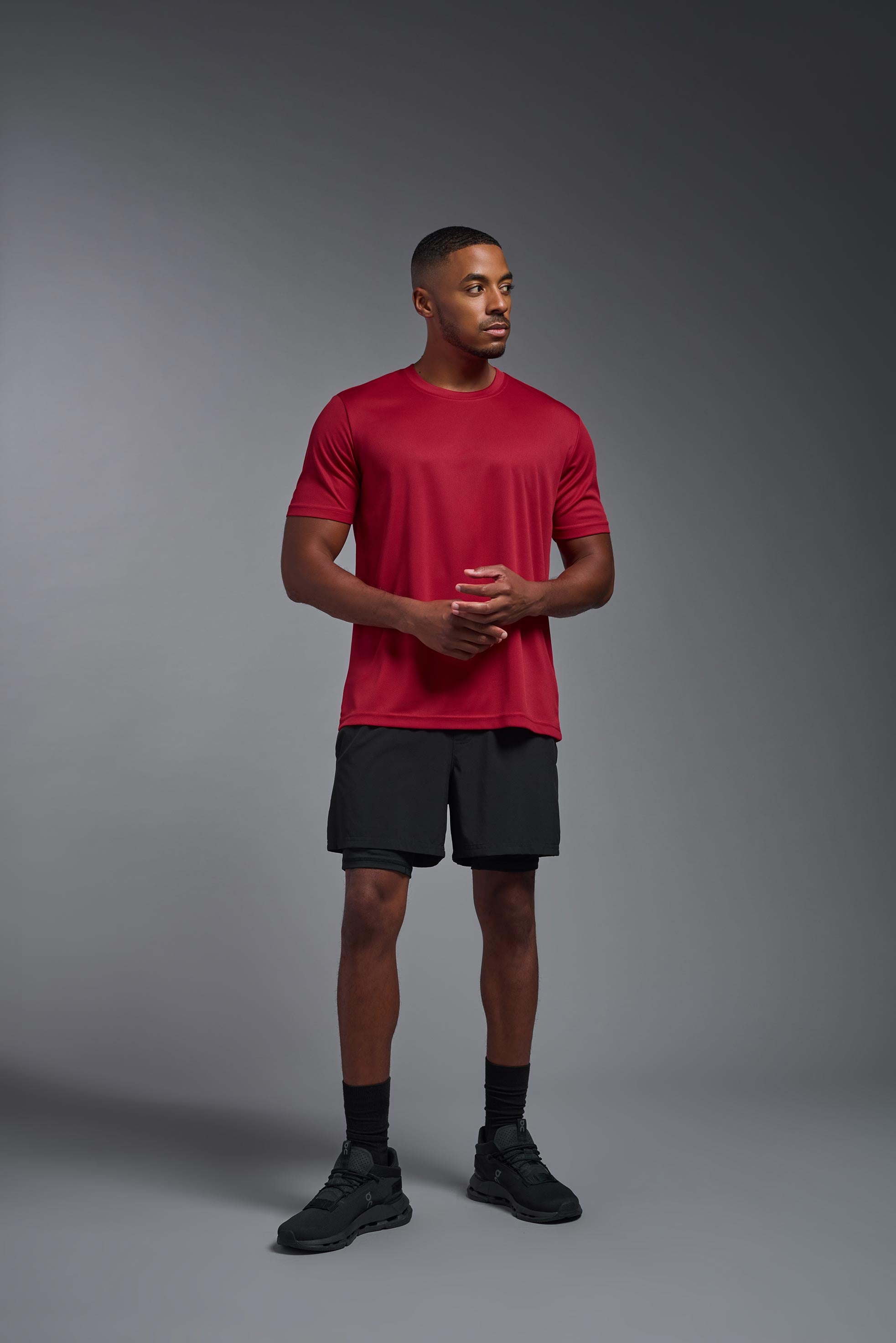 A male model wearing the men's Oxymesh Crewneck Tech Tee in the color true red made out of 100% polyester, showing the relaxed fit from a back view. This shirt is breathable, wicks away moisture, quick-dries, and is made in the USA. #true-red
