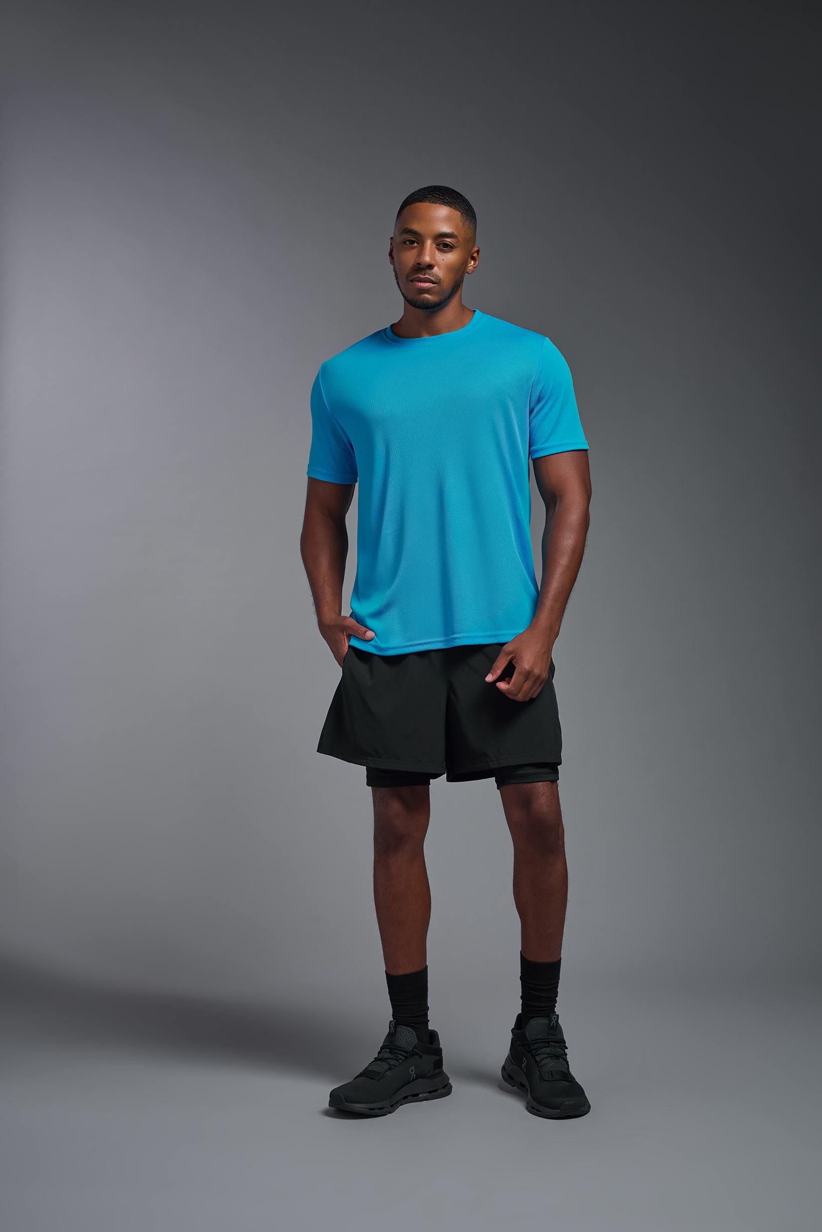 A male model wearing the men's Oxymesh Crewneck Tech Tee in the color turquoise made out of 100% polyester, showing the relaxed fit from a turquoise front view. This shirt is breathable, wicks away moisture, quick-dries, and is made in the USA. #turquoise