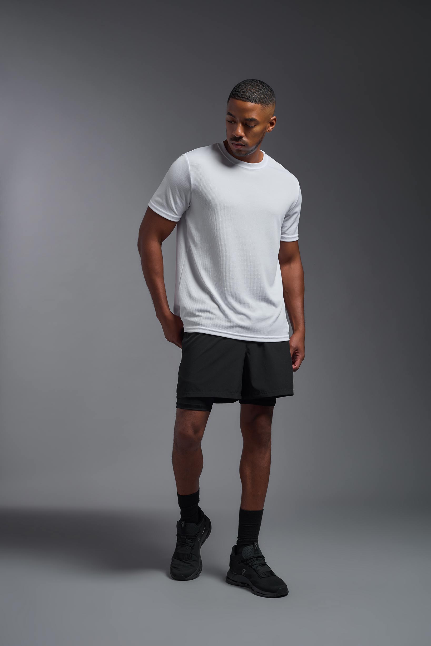 A male model wearing the men's Oxymesh Crewneck Tech Tee in the color white made out of 100% polyester, showing the relaxed fit from a front view. This shirt is breathable, wicks away moisture, quick-dries, and is made in the USA. #white