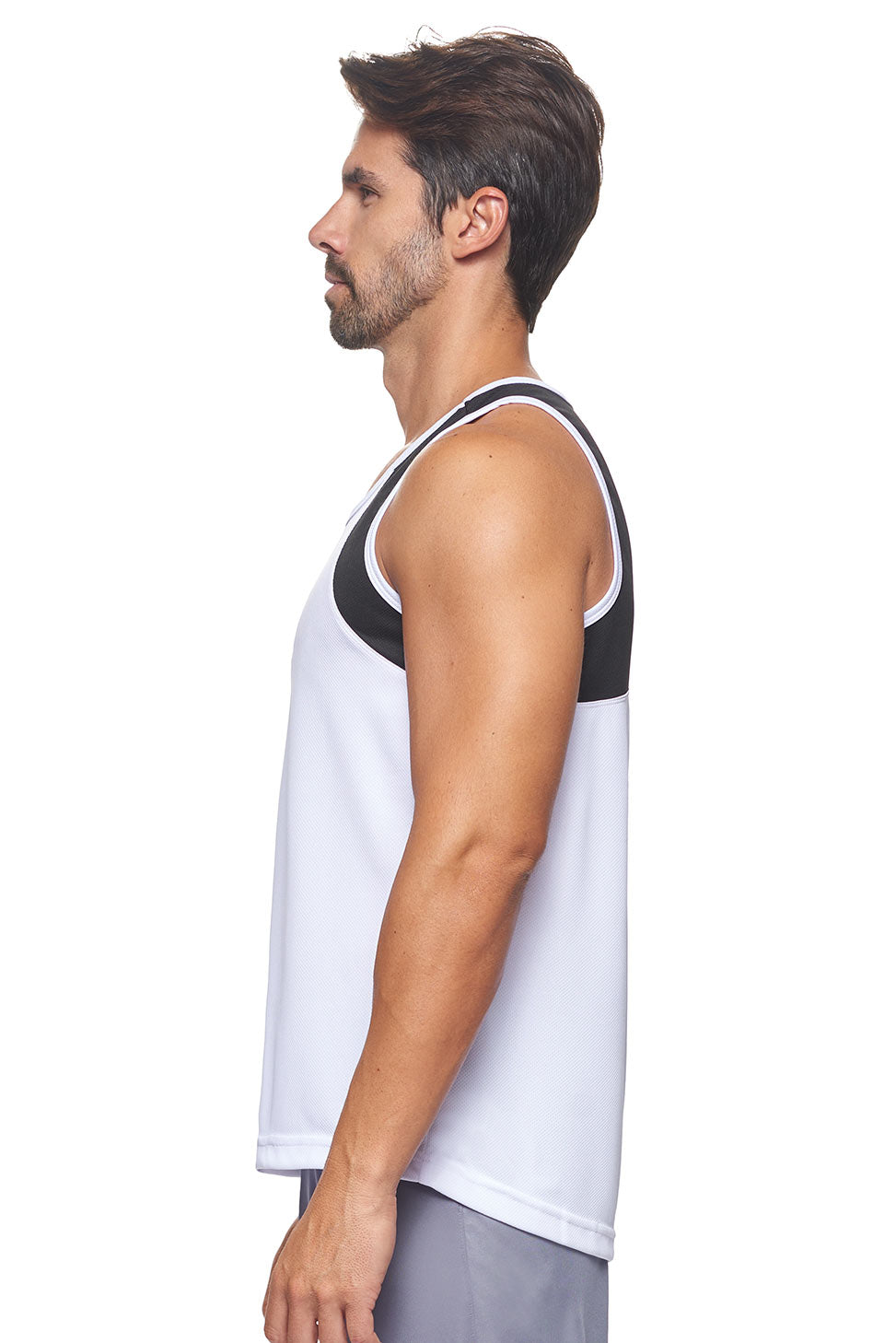 A male model wearing the men's Oxymesh Distance Tank  in the color block white and black, made out of 100% polyester, showing the relaxed fit from a front side view. This tank is quick-drying, moisture-wicking, with up to 30 UV protection and made in the USA. #white