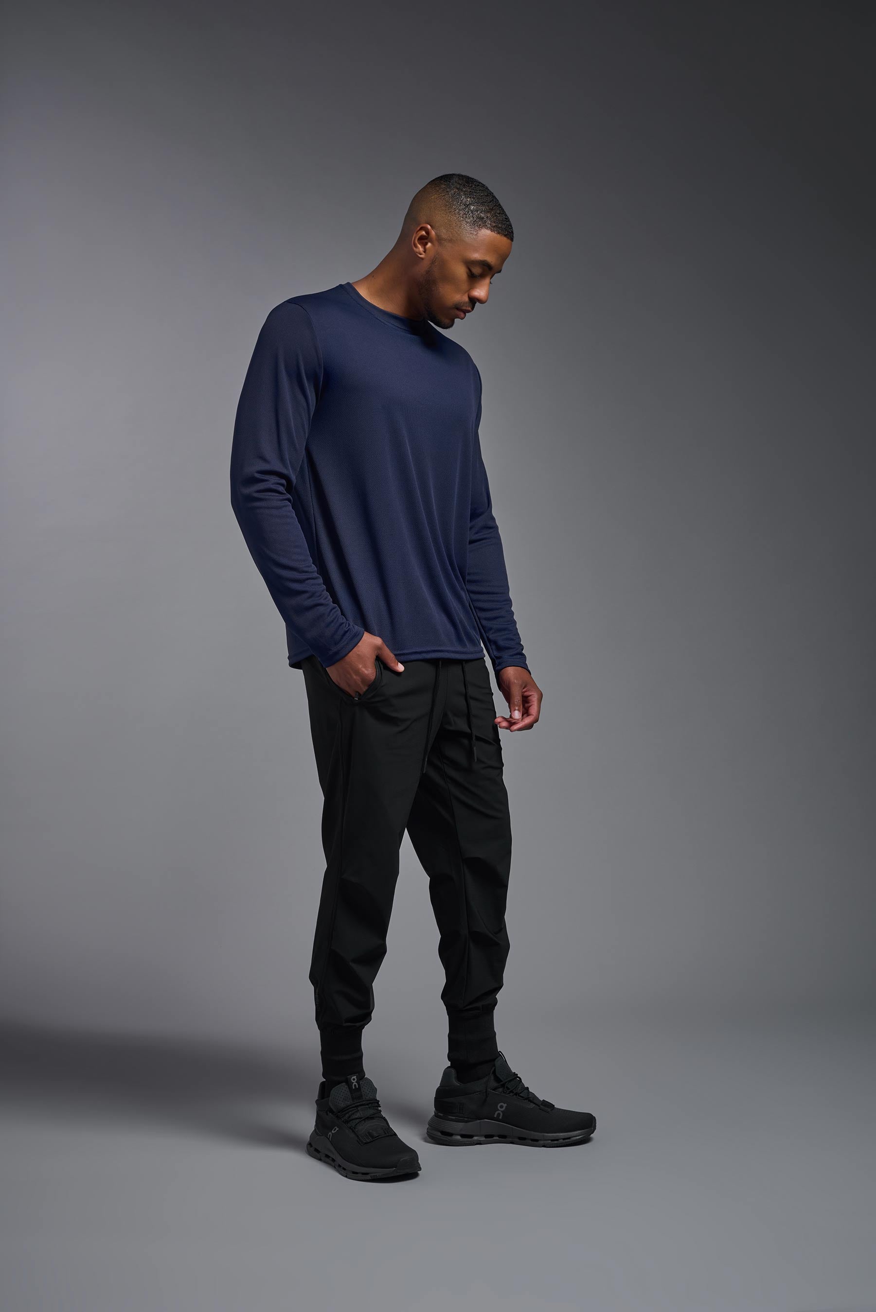 A male model wearing the men's Oxymesh Long Sleeve Tech Tee Imported Version in the color navy-blue, made out of 100% polyester, showing the relaxed fit from a side view. This shirt is breathable, quick-drying, moisture-wicking, and Imported for a better price on bulk apparel. #navy-blue