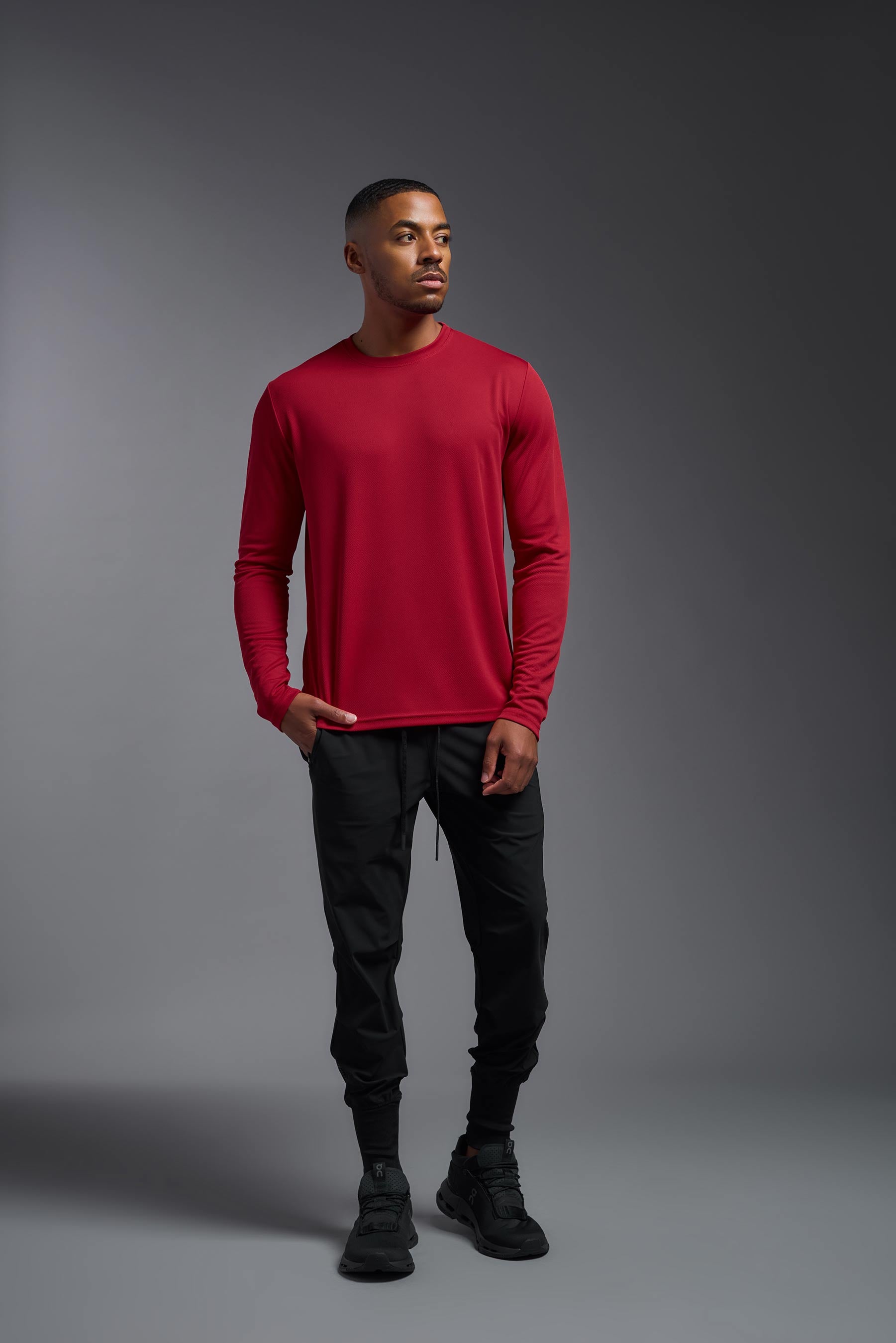 A male model wearing the men's Oxymesh Long Sleeve Tech Tee Imported Version in the color true red, made out of 100% polyester, showing the relaxed fit from a front view. This shirt is breathable, quick-drying, moisture-wicking, and Imported for a better price on bulk apparel. #true-red