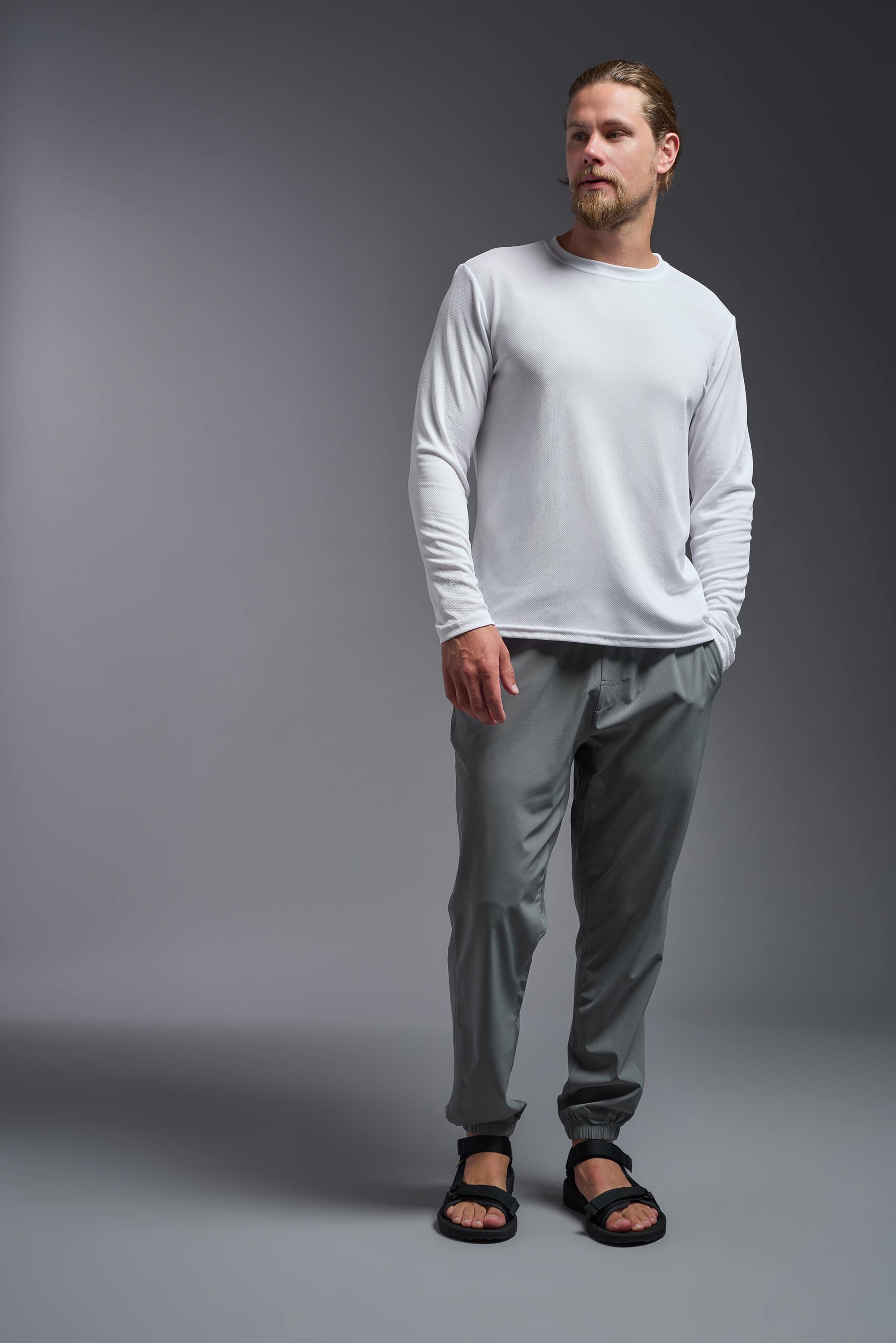 A male model wearing the men's Oxymesh Long Sleeve Tech Tee Imported Version in the color white, made out of 100% polyester, showing the relaxed fit from a front view. This shirt is breathable, quick-drying, moisture-wicking, and Imported for a better price on bulk apparel. #white