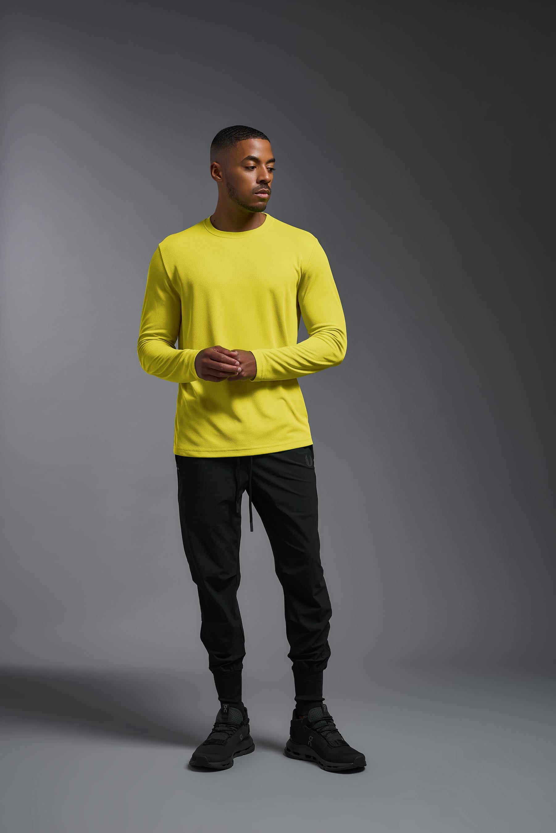 A male model wearing the men's Oxymesh Long Sleeve Tech Tee in the bright yellow made out of 100% polyester, showing the relaxed fit from a back view. This shirt is breathable, quick-drying, moisture-wicking, and made in the USA. #bright-yellow