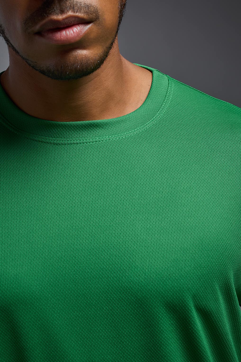 A male model wearing the men's Oxymesh Long Sleeve Tech Tee in the color kelly green, made out of 100% polyester, showing the relaxed fit from a close-up collar front view. This shirt is breathable, quick-drying, moisture-wicking, and made in the USA. #kelly-green