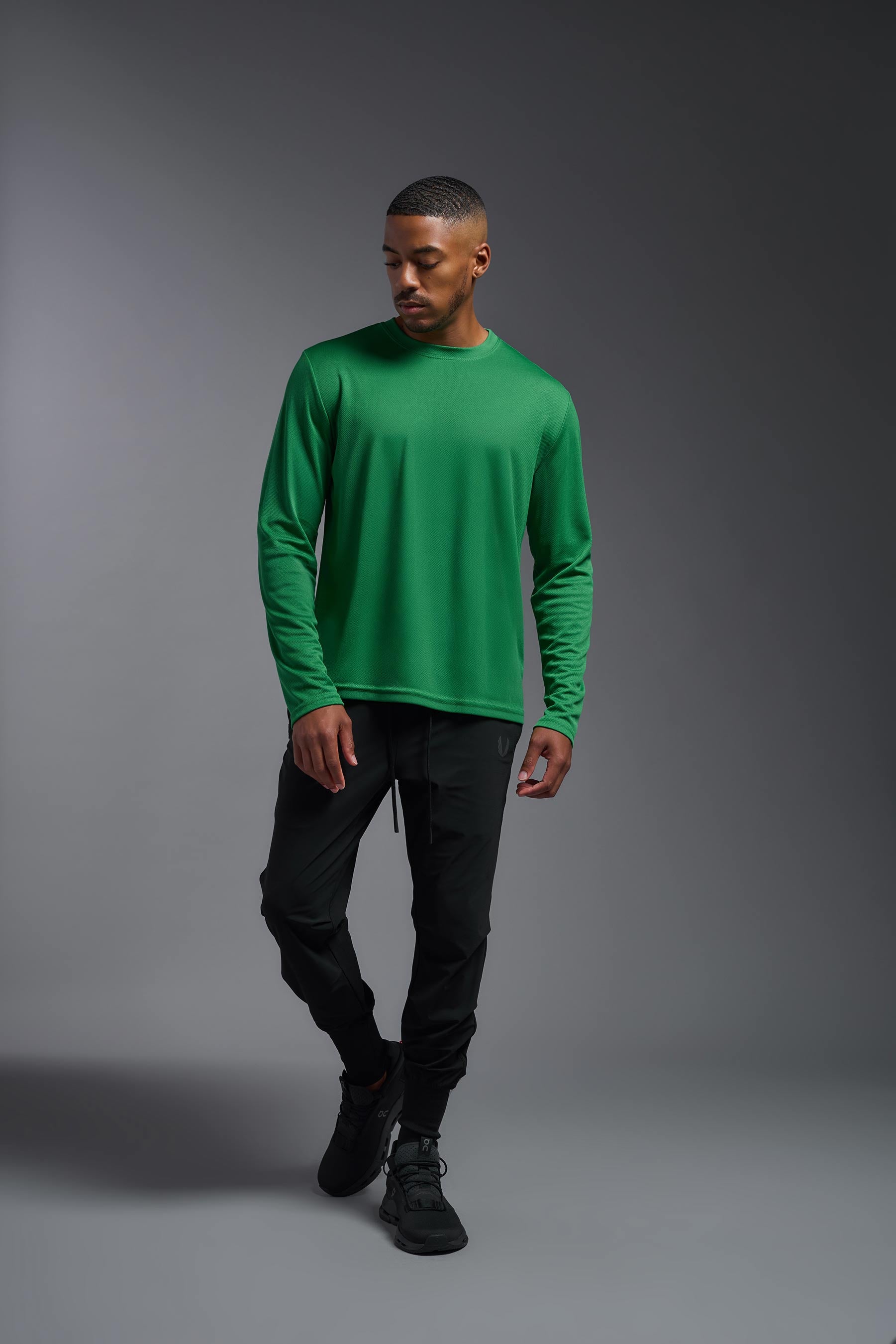 A male model wearing the men's Oxymesh Long Sleeve Tech Tee in the color kelly green, made out of 100% polyester, showing the relaxed fit from a front view. This shirt is breathable, quick-drying, moisture-wicking, and made in the USA. #kelly-green