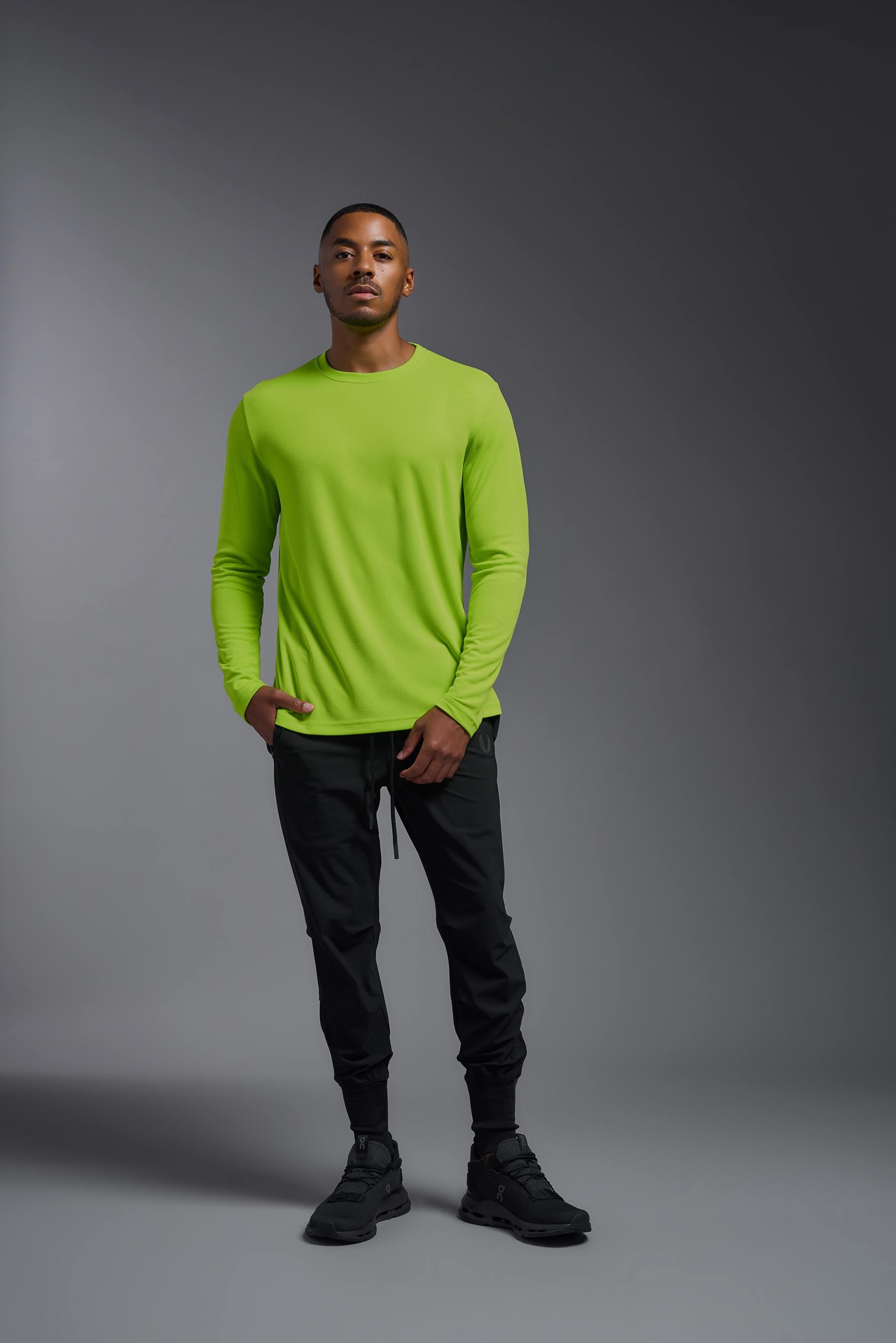 A male model wearing the men's Oxymesh Long Sleeve Tech Tee in the color key lime, made out of 100% polyester, showing the relaxed fit from a front view. This shirt is breathable, quick-drying, moisture-wicking, and made in the USA. #key-lime