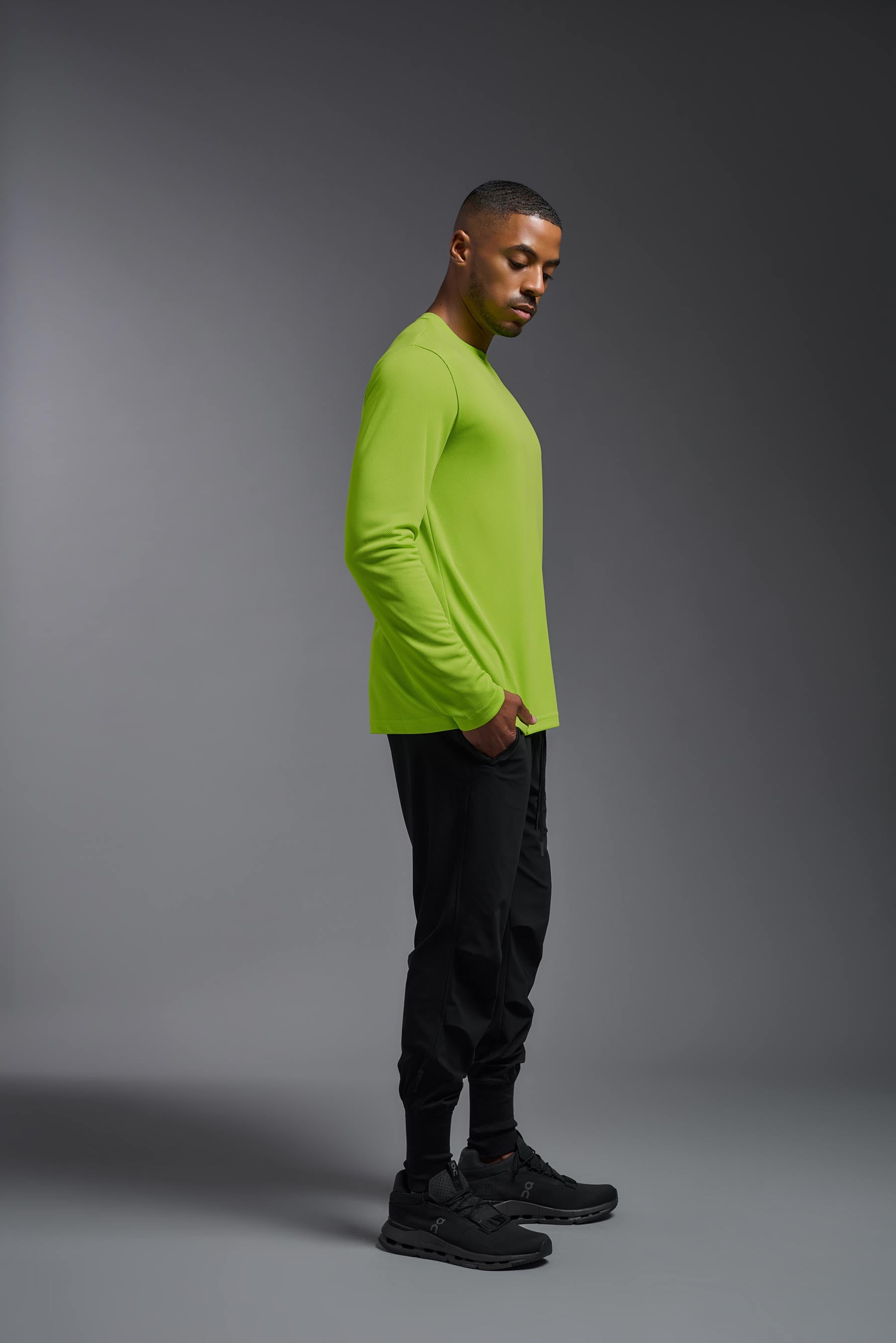 A male model wearing the men's Oxymesh Long Sleeve Tech Tee in the color key lime, made out of 100% polyester, showing the relaxed fit from a side view. This shirt is breathable, quick-drying, moisture-wicking, and made in the USA. #key-lime