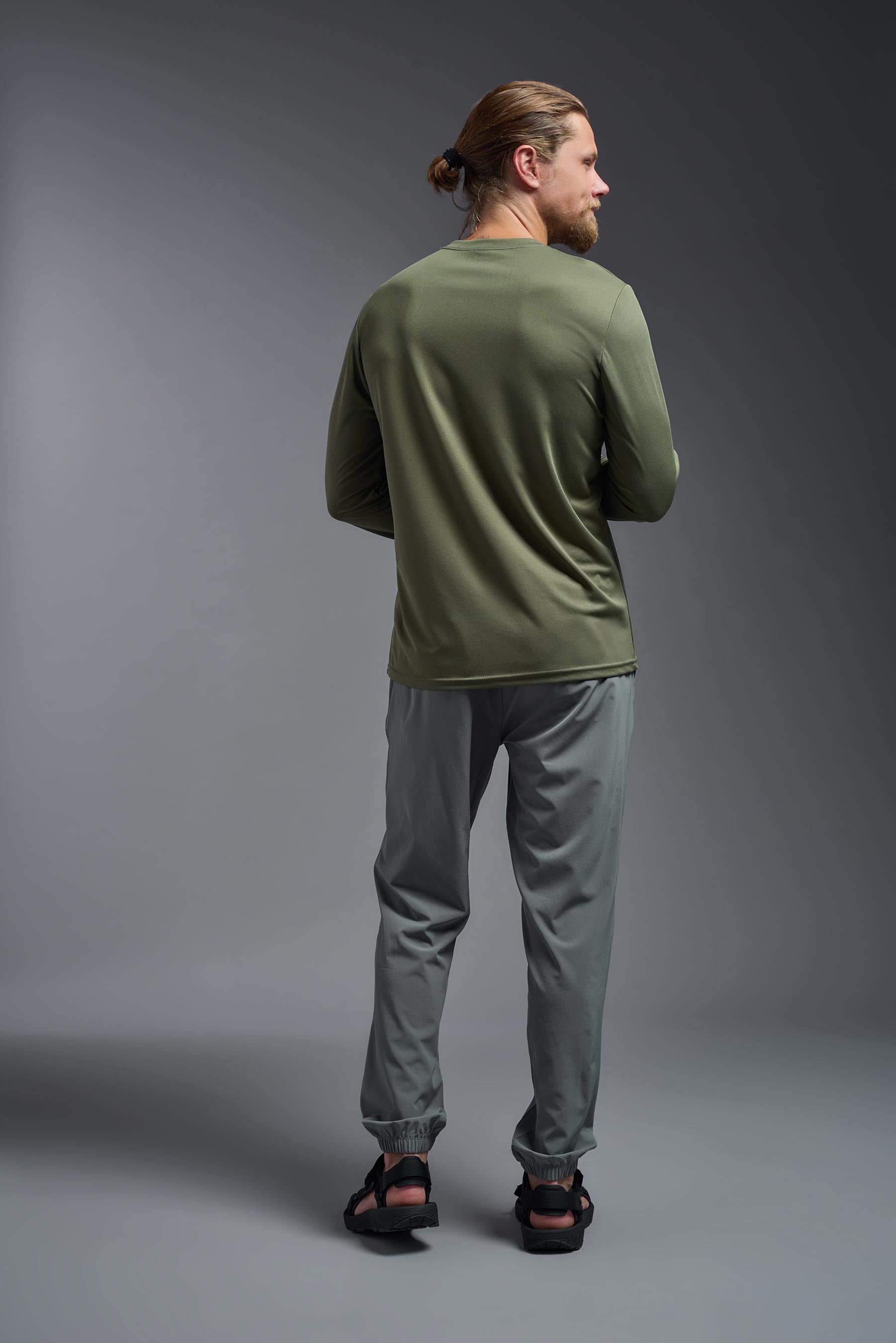 A male model wearing the men's Oxymesh Long Sleeve Tech Tee in the color military green, made out of 100% polyester, showing the relaxed fit from a close-up collar view. This shirt is breathable, quick-drying, moisture-wicking, and made in the USA. #military-green