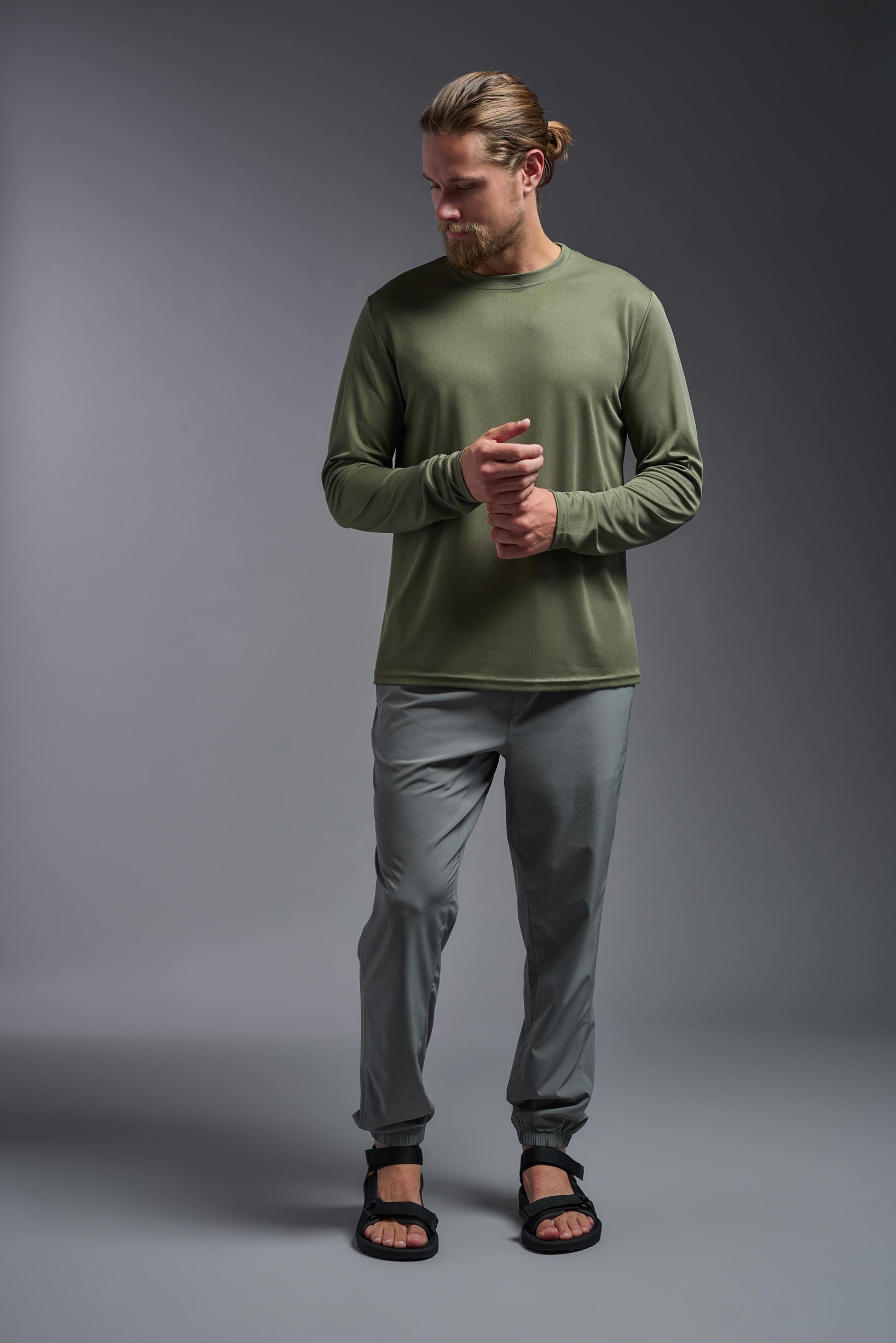 A male model wearing the men's Oxymesh Long Sleeve Tech Tee in the color military green, made out of 100% polyester, showing the relaxed fit from a front view. This shirt is breathable, quick-drying, moisture-wicking, and made in the USA. #military-green