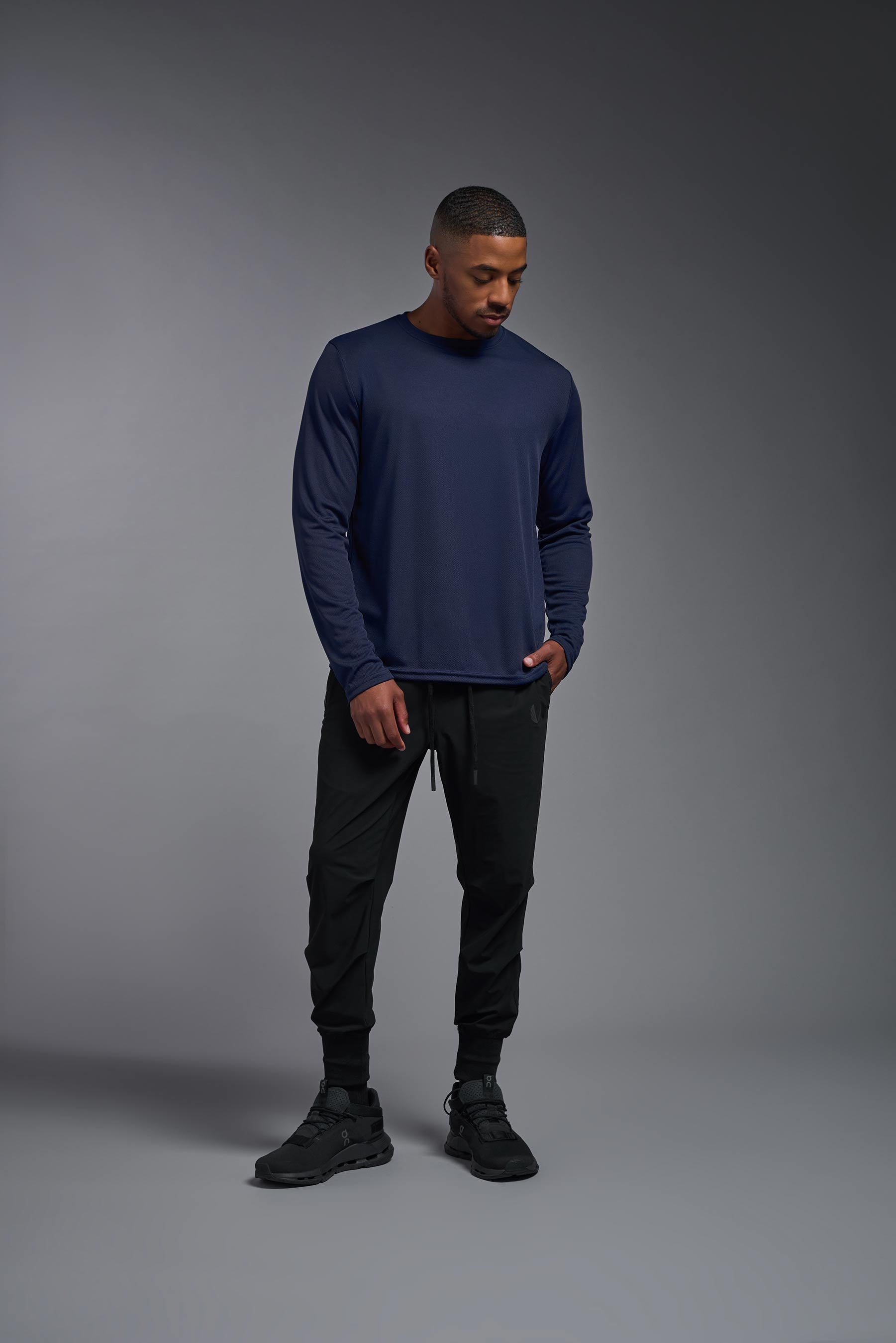A male model wearing the men's Oxymesh Long Sleeve Tech Tee in the color navy blue, made out of 100% polyester, showing the relaxed fit from a front view. This shirt is breathable, quick-drying, moisture-wicking, and made in the USA. #navy-blue