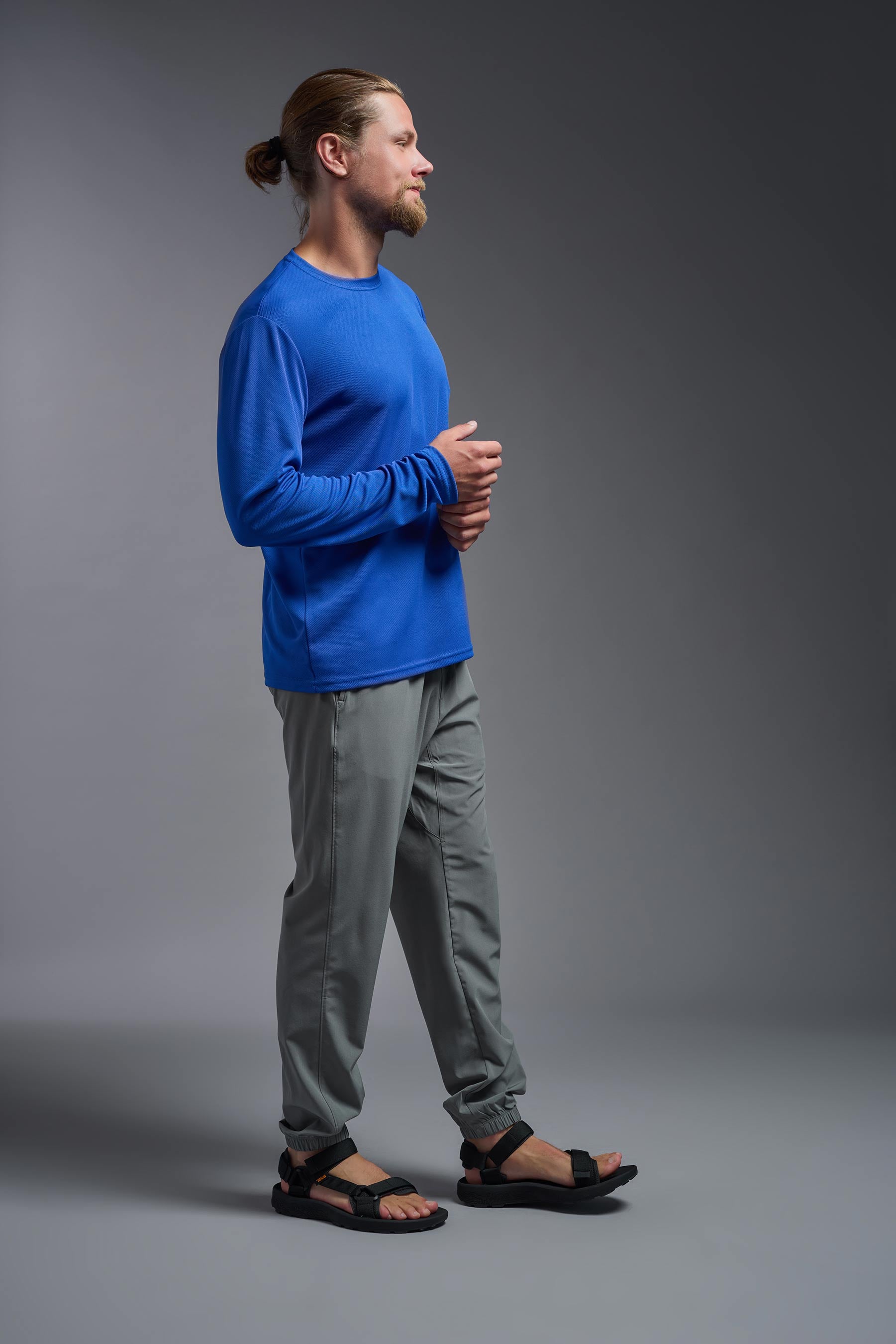 A male model wearing the men's Oxymesh Long Sleeve Tech Tee in the color royal blue, made out of 100% polyester, showing the relaxed fit from a side view. This shirt is breathable, quick-drying, moisture-wicking, and made in the USA. #royal-blue