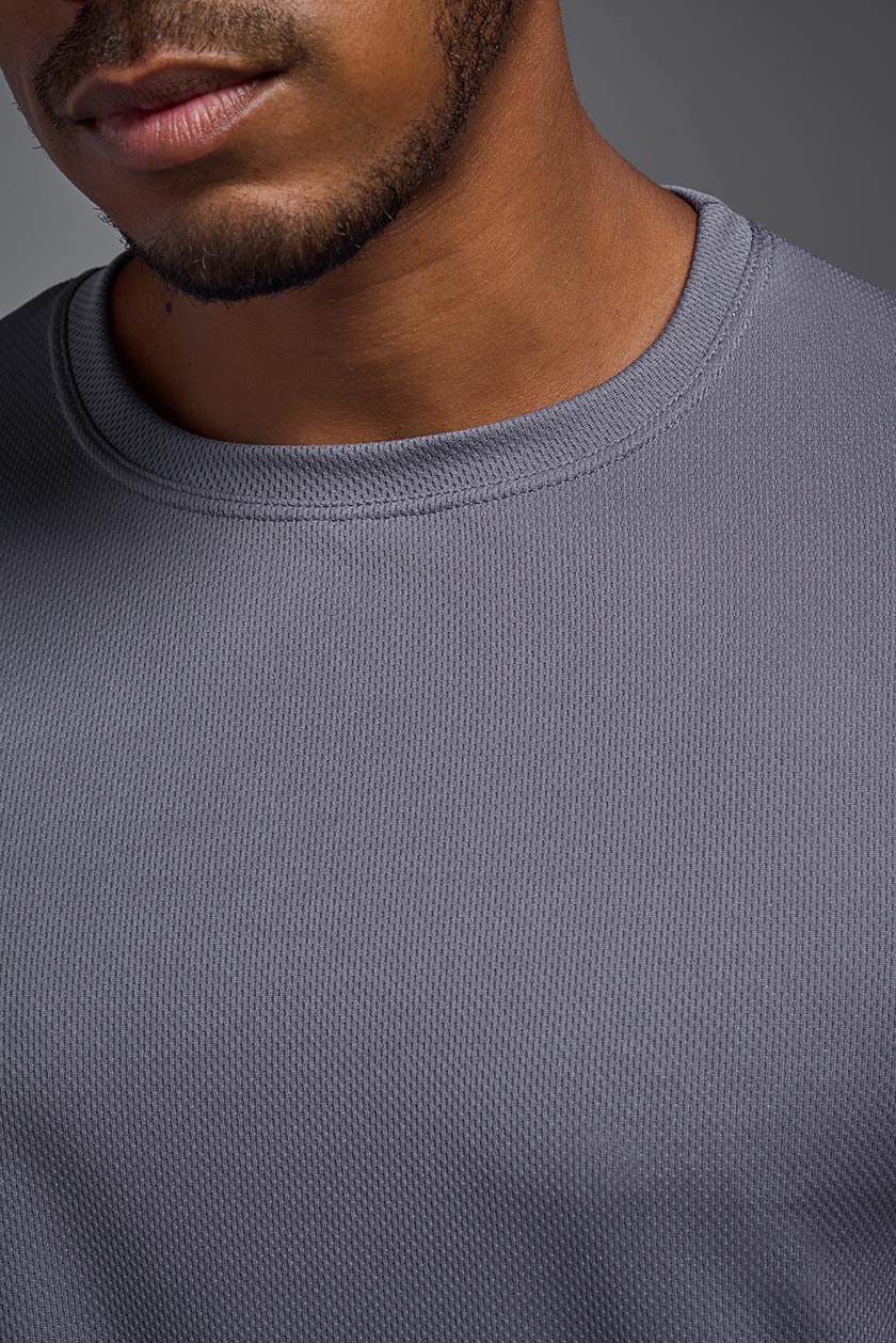 A male model wearing the men's Oxymesh Long Sleeve Tech Tee in the color steel gray made out of 100% polyester, showing the relaxed fit from a close-up collar view. This shirt is breathable, quick-drying, moisture-wicking, and made in the USA. #steel-gray