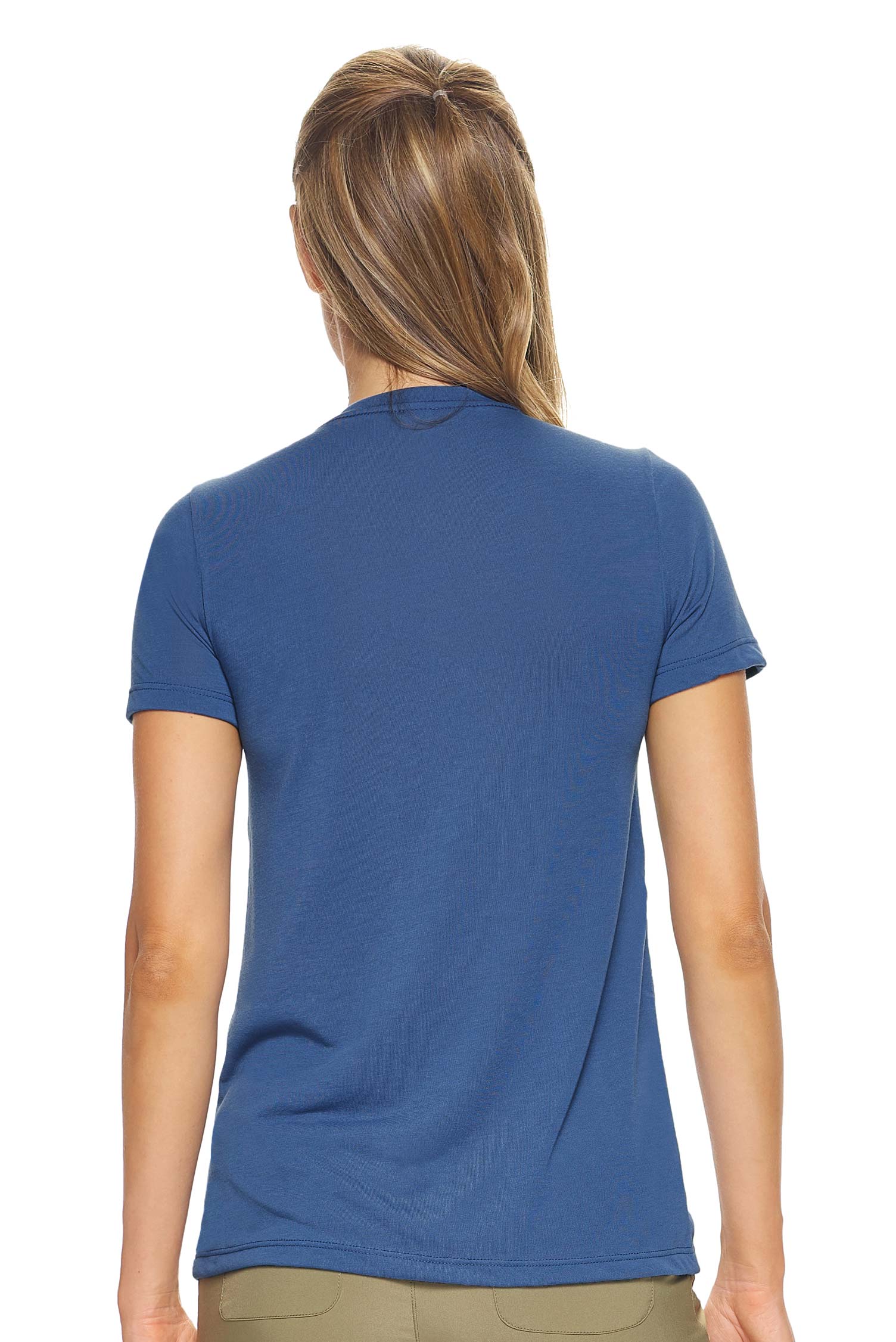 A female model with brown hair on a white background wearing the women's Siro™ V-Neck Tee in the color stone blue, made out of 100% snag-free filament polyester, showing the modern fit from a back view. This women's v-neck shirt is breathable, quick-drying, moisture-wicking, and made in the USA. Available in bulk for wholesale purchase. #stone-blue