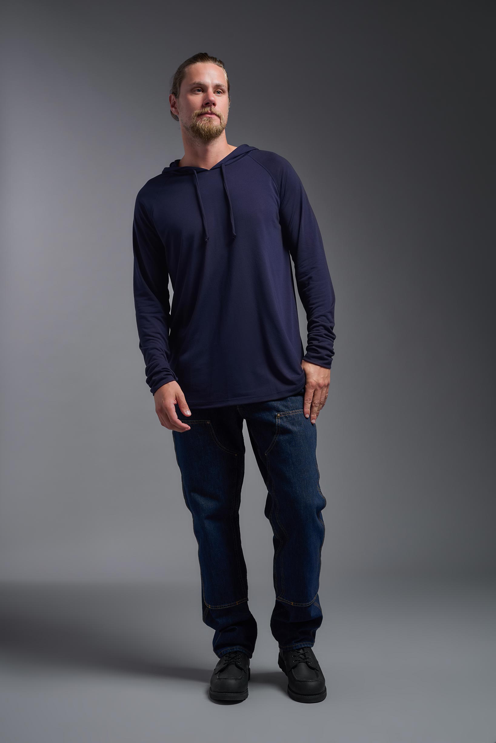 A male model wearing the men's Siro™ Hoodie Shirt in the color navy, made out of 100% polyester, showing the relaxed fit from a front view. This long sleeve hoodie shirt is breathable, quick-drying, moisture-wicking, and made in the USA. #navy