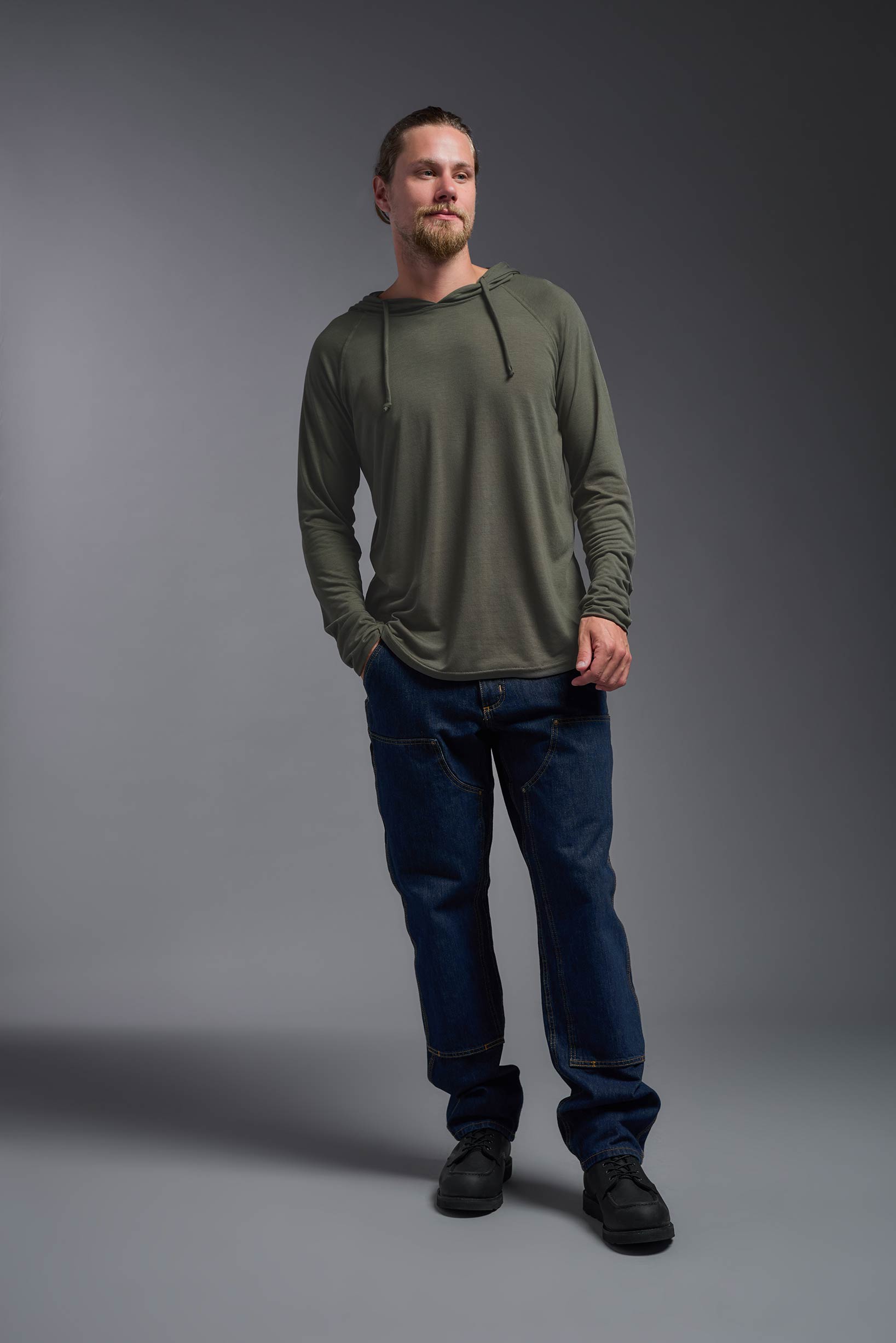 A male model wearing the men's Siro™ Hoodie Shirt in the color olive, made out of 100% polyester, showing the relaxed fit from a front view. This long sleeve hoodie shirt is breathable, quick-drying, moisture-wicking, and made in the USA. #olive