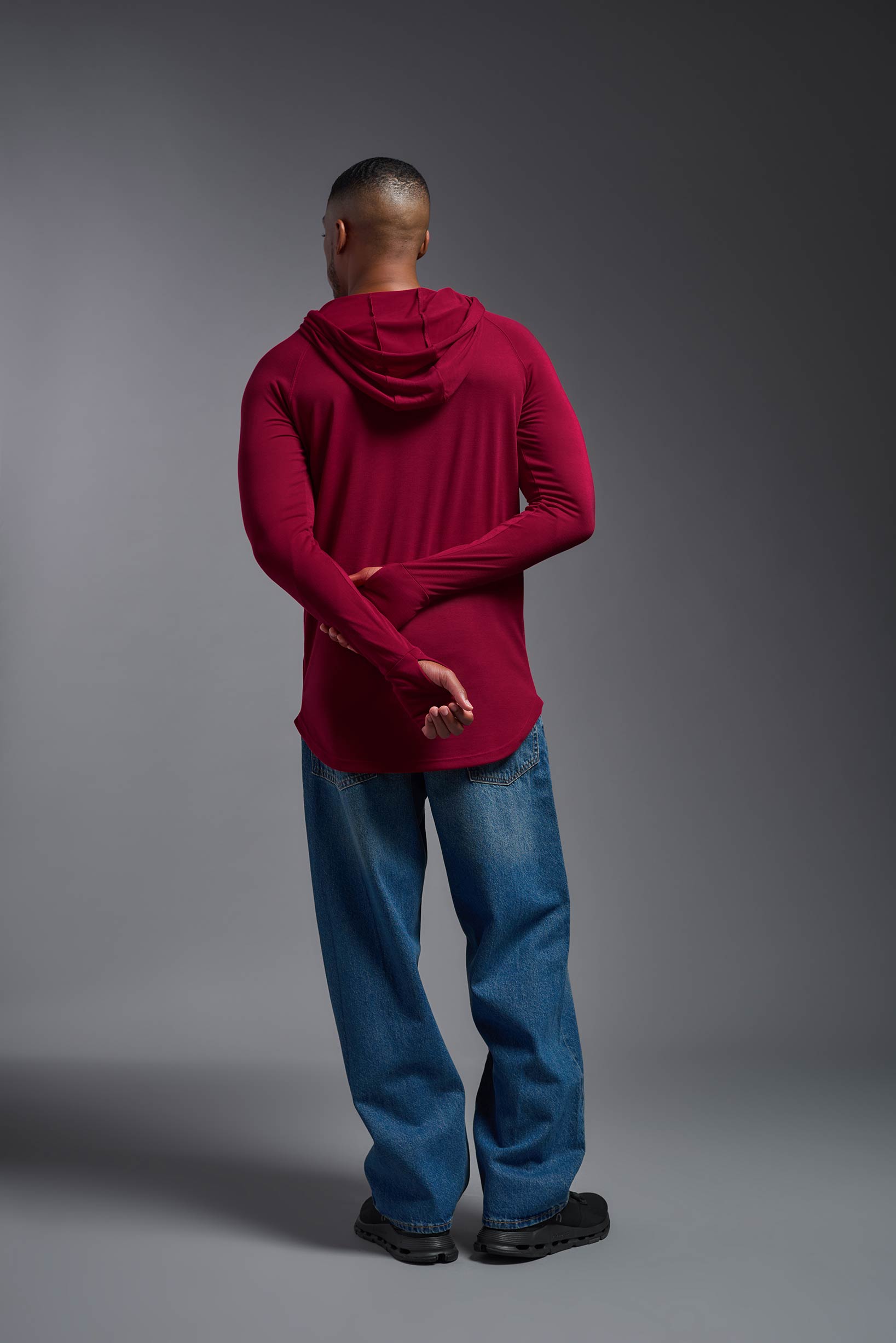 A male model wearing the men's Siro™ Hoodie Shirt in the color scarlet, made out of 100% polyester, showing the relaxed fit from a back view. This long sleeve hoodie shirt is breathable, quick-drying, moisture-wicking, and made in the USA. #scarlet