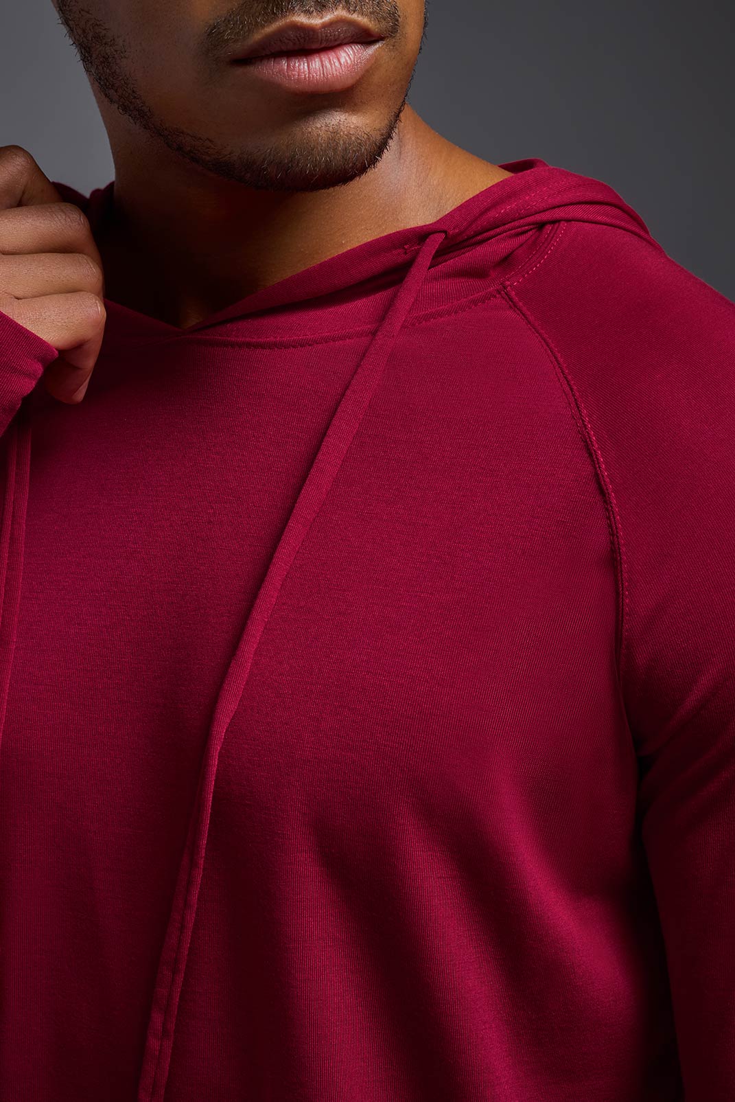 A male model wearing the men's Siro™ Hoodie Shirt in the color scarlet, made out of 100% polyester, showing the relaxed fit from a closeup collar view. This long sleeve hoodie shirt is breathable, quick-drying, moisture-wicking, and made in the USA. #scarlet