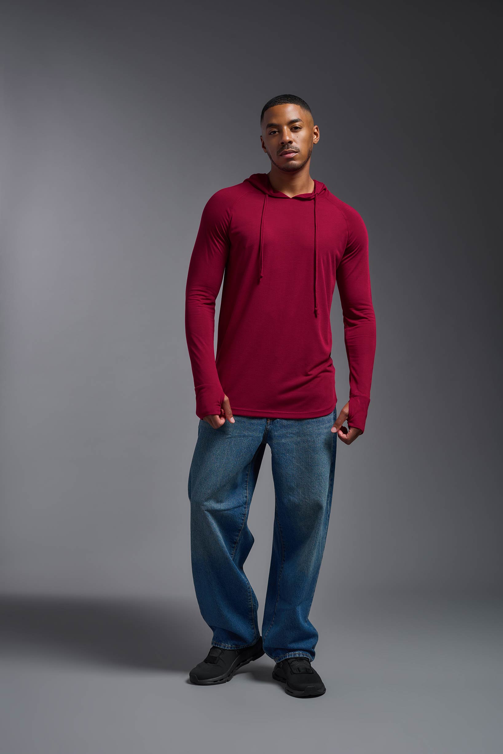 A male model wearing the men's Siro™ Hoodie Shirt in the color scarlet, made out of 100% polyester, showing the relaxed fit from a front view. This long sleeve hoodie shirt is breathable, quick-drying, moisture-wicking, and made in the USA. #scarlet