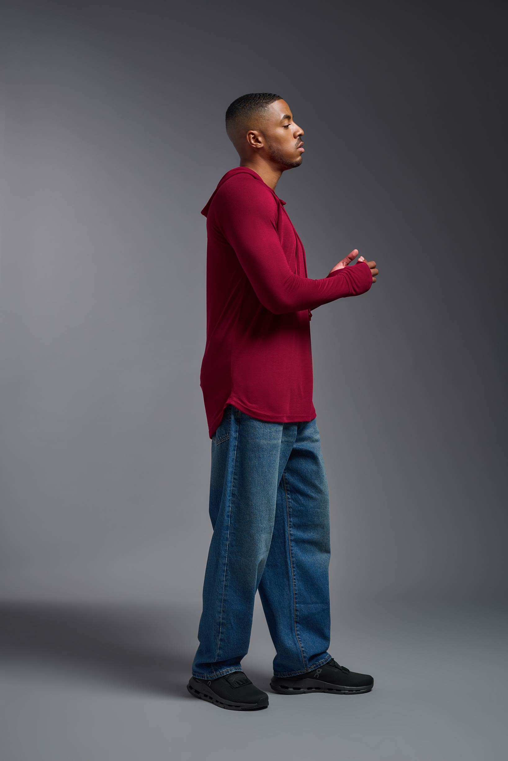 A male model wearing the men's Siro™ Hoodie Shirt in the color scarlet, made out of 100% polyester, showing the relaxed fit from a side view. This long sleeve hoodie shirt is breathable, quick-drying, moisture-wicking, and made in the USA. #scarlet