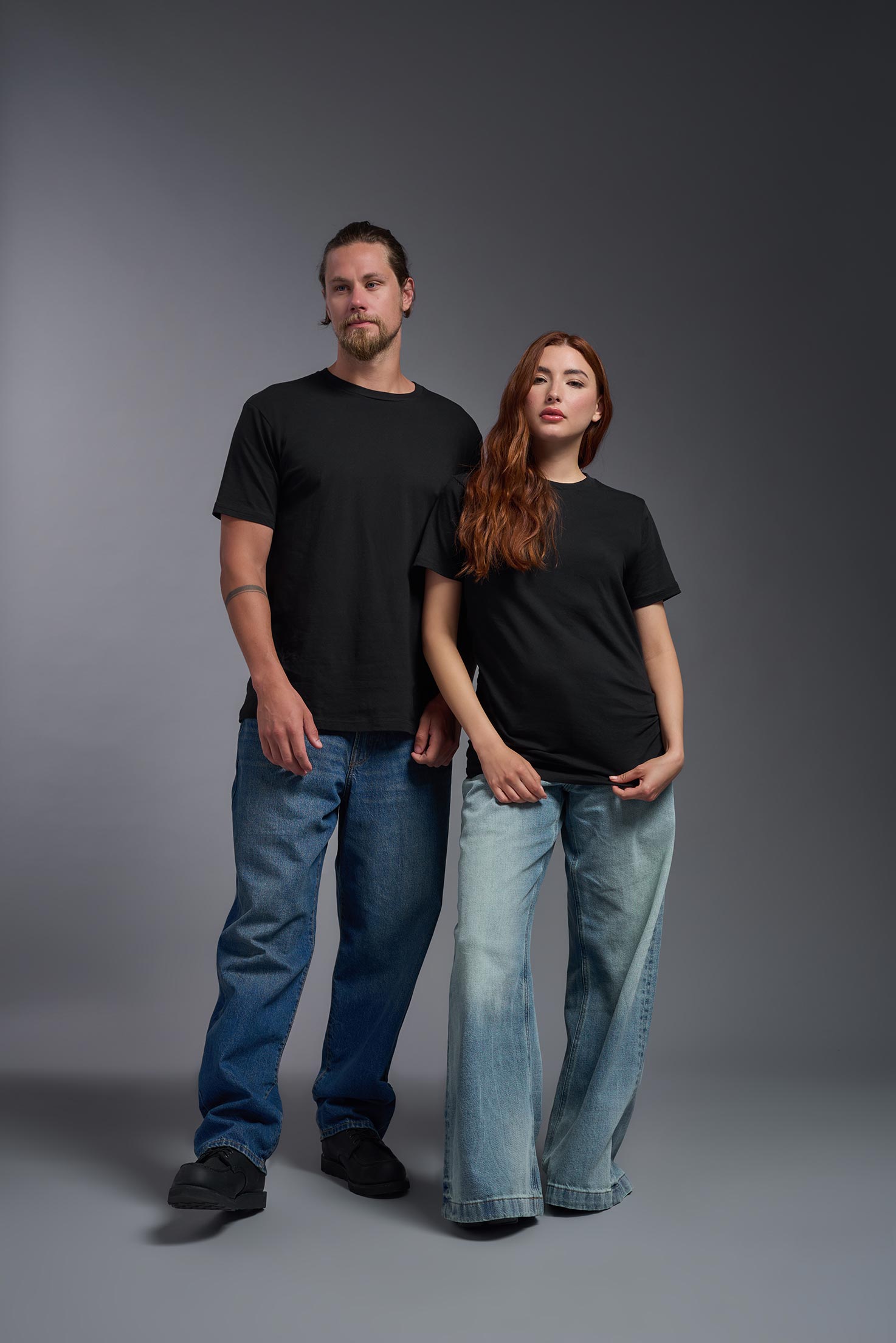 A male and female model wearing the unisex Americana Cotton Soft Tee in the color black, made from 100% combed ring-spun USA-grown cotton, showing the classic fit from a front view. This premium shirt is Made in the USA. #black