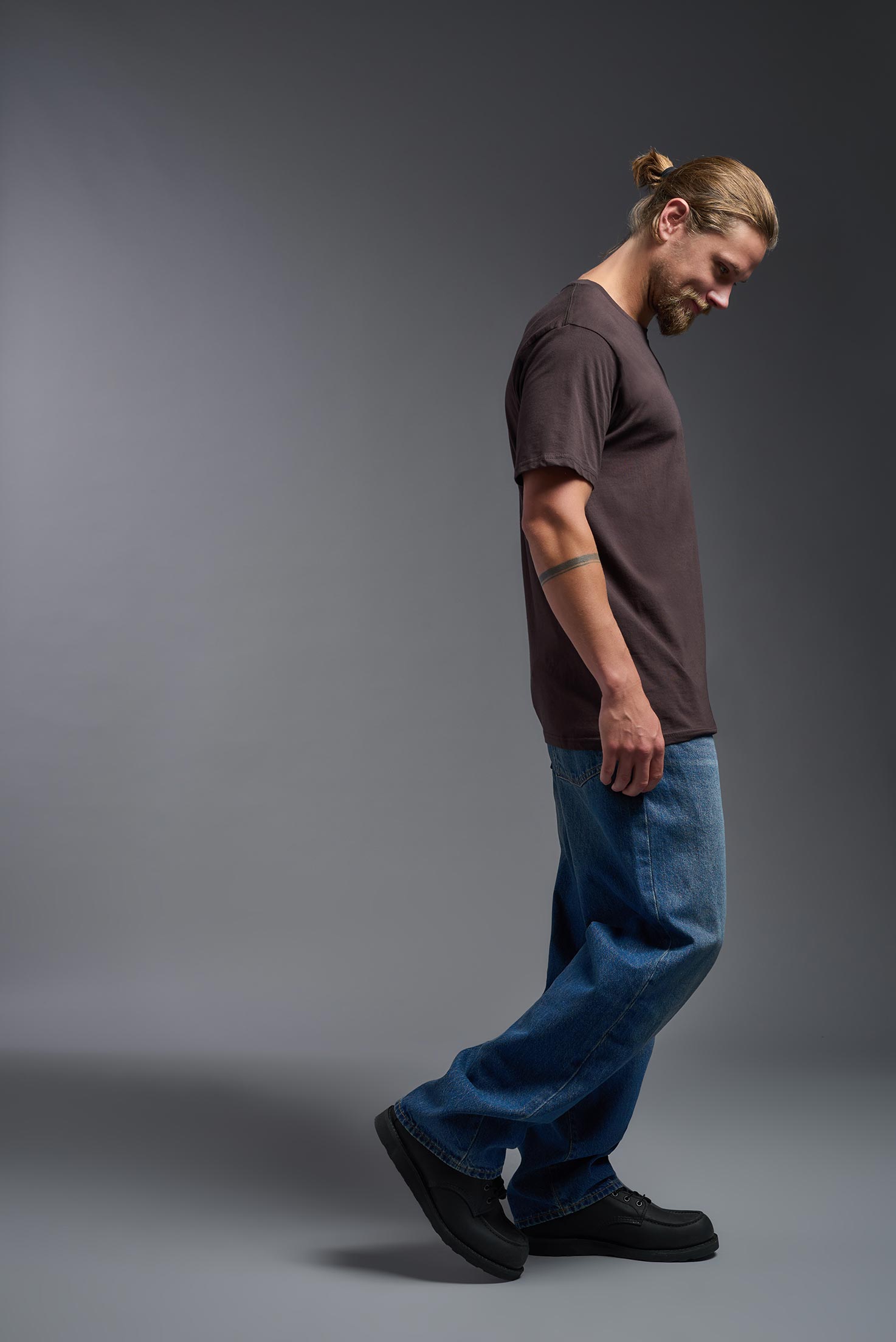 A male model wearing the unisex Americana Cotton Soft Tee in the color brown, made from 100% combed ring-spun USA-grown cotton, showing the classic fit from a side view. This premium shirt is Made in the USA. #brown