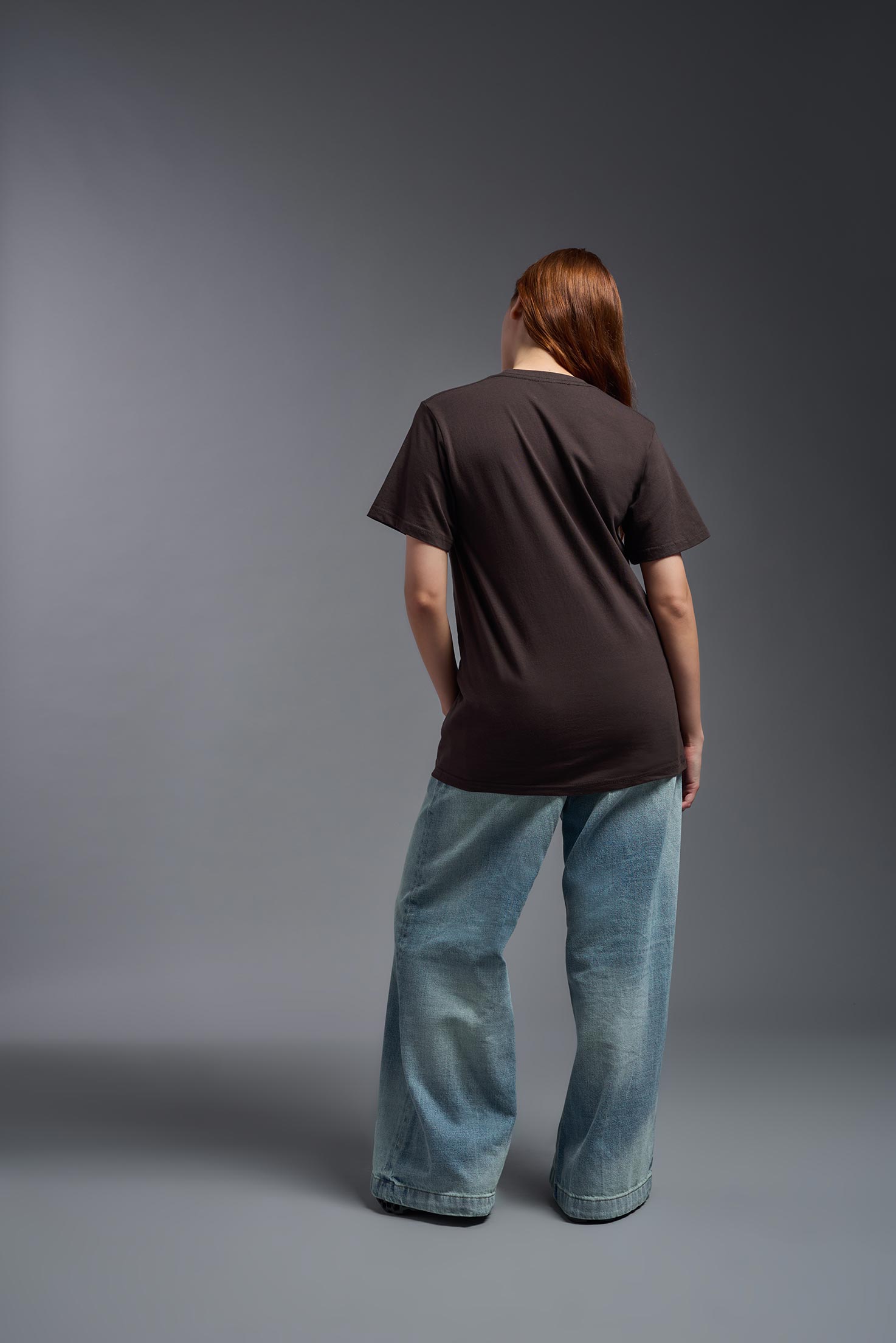 A female model wearing the unisex Americana Cotton Soft Tee in the color brown, made from 100% combed ring-spun USA-grown cotton, showing the classic fit from a back view. This premium shirt is Made in the USA. #brown