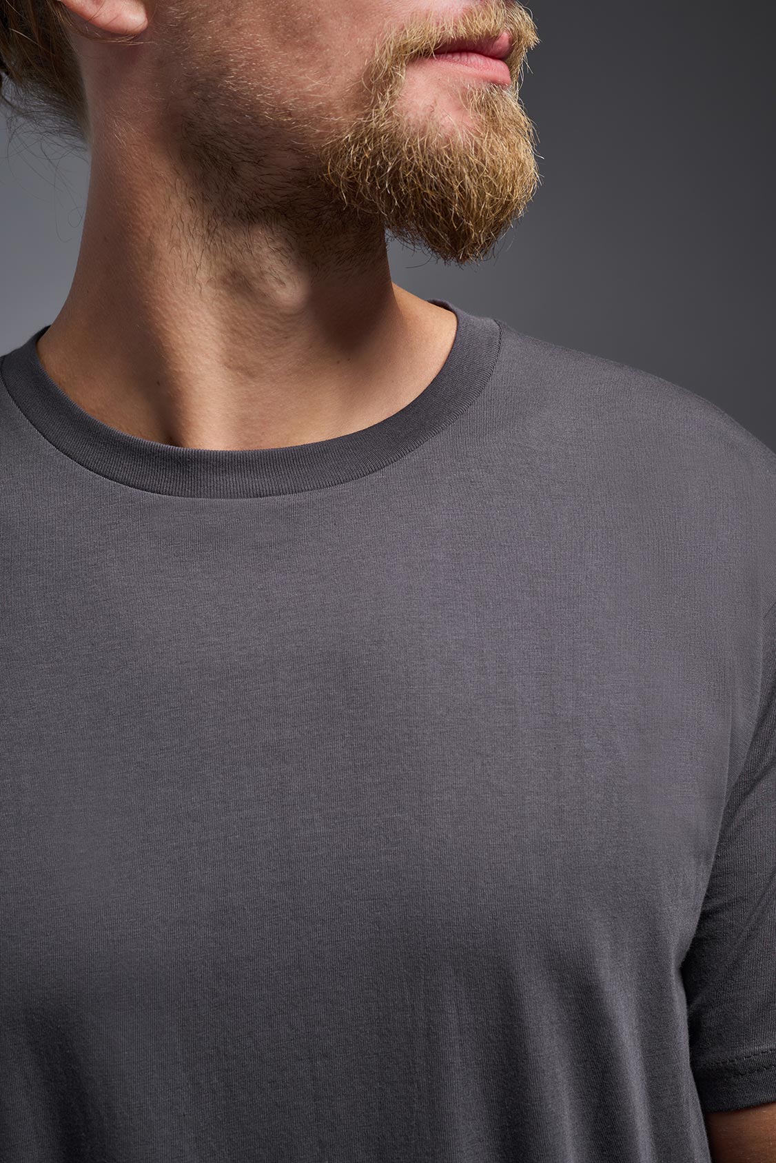 A male model wearing the unisex Americana Cotton Soft Tee in the color charcoal, made from 100% combed ring-spun USA-grown cotton, showing the classic fit from a close-up collar view. This premium shirt is Made in the USA. #charcoal