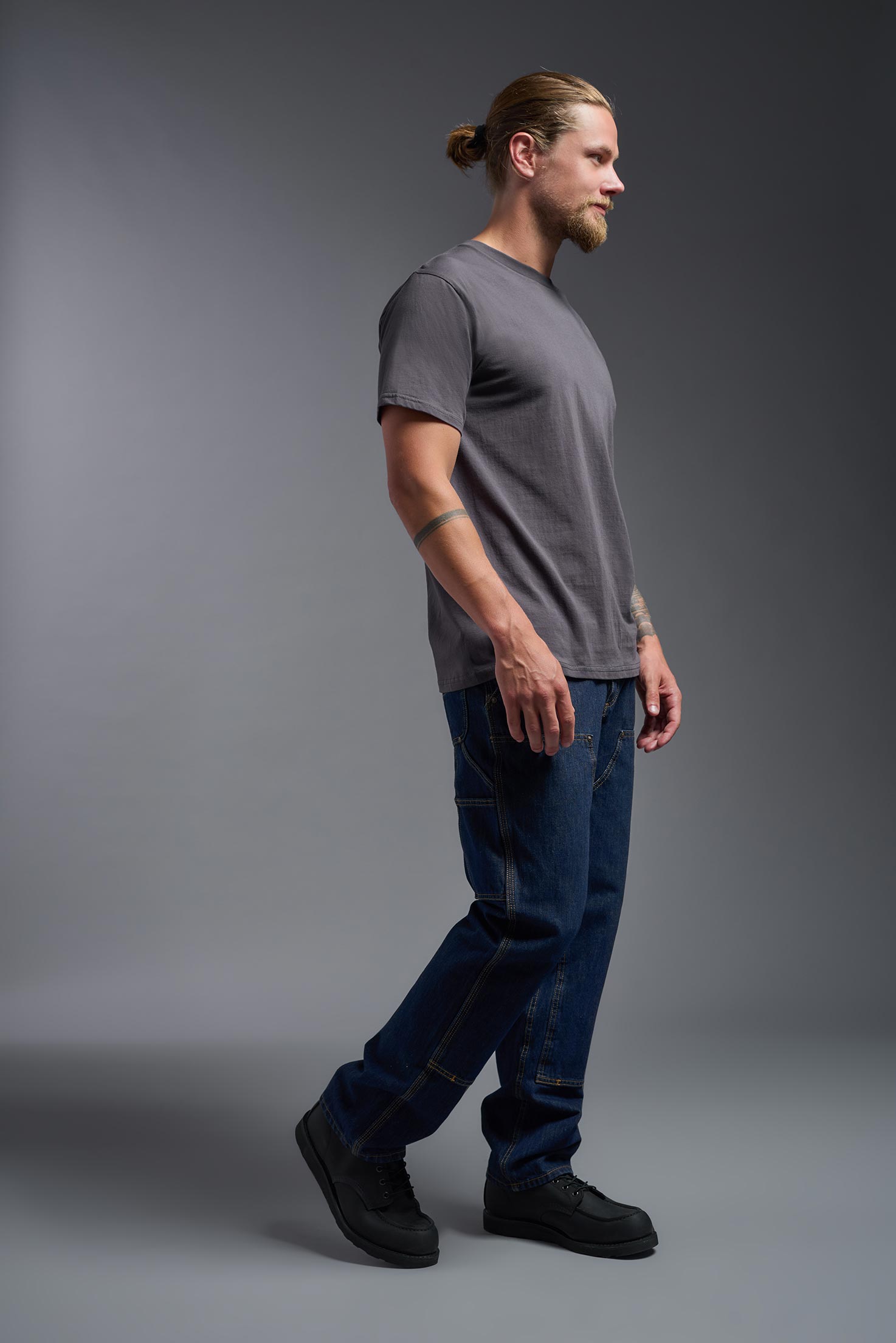 A male model wearing the unisex Americana Cotton Soft Tee in the color charcoal, made from 100% combed ring-spun USA-grown cotton, showing the classic fit from a side view. This premium shirt is Made in the USA. #charcoal